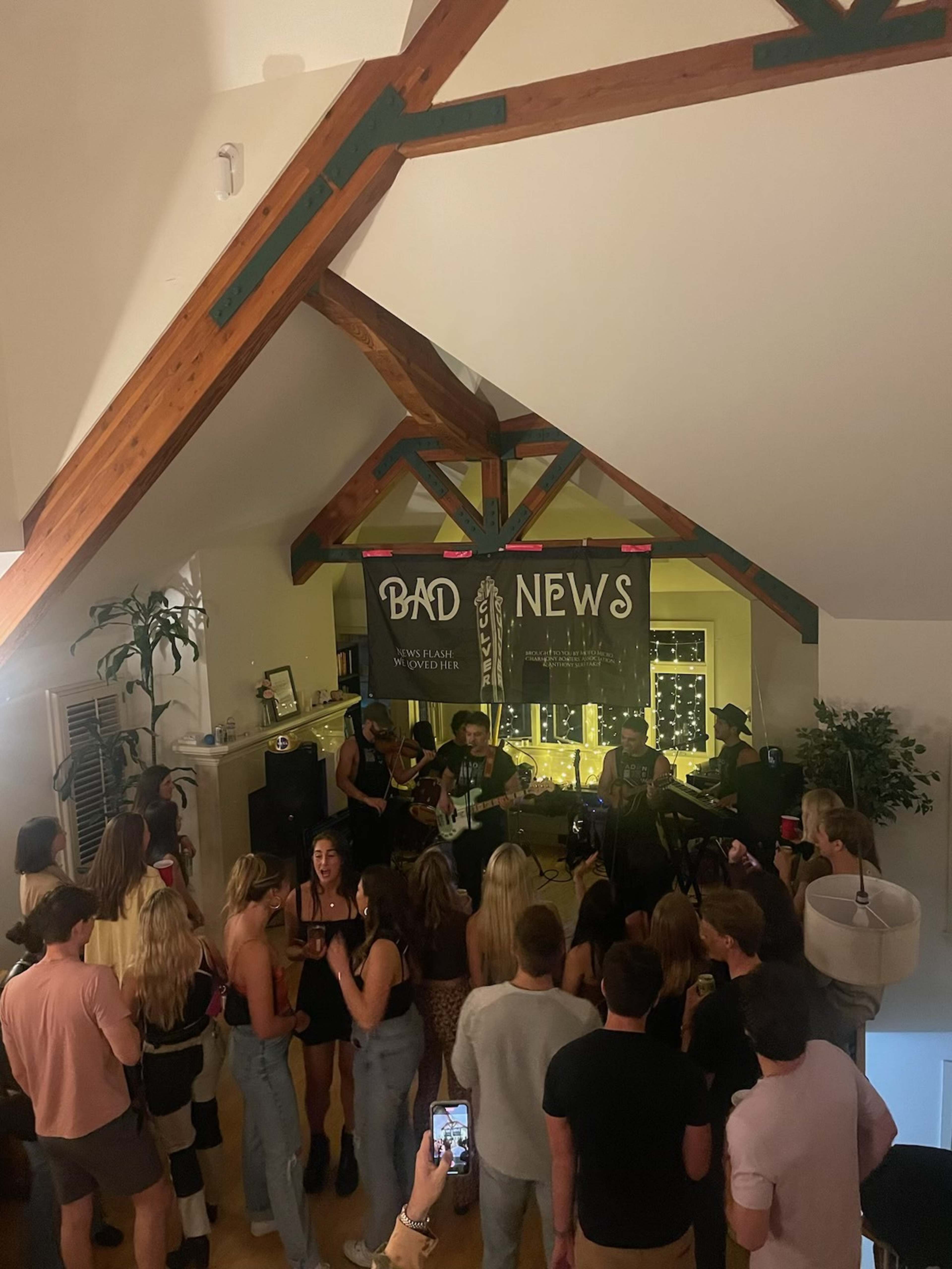 A band performs in a loft space filled with people watching and enjoying the live music.