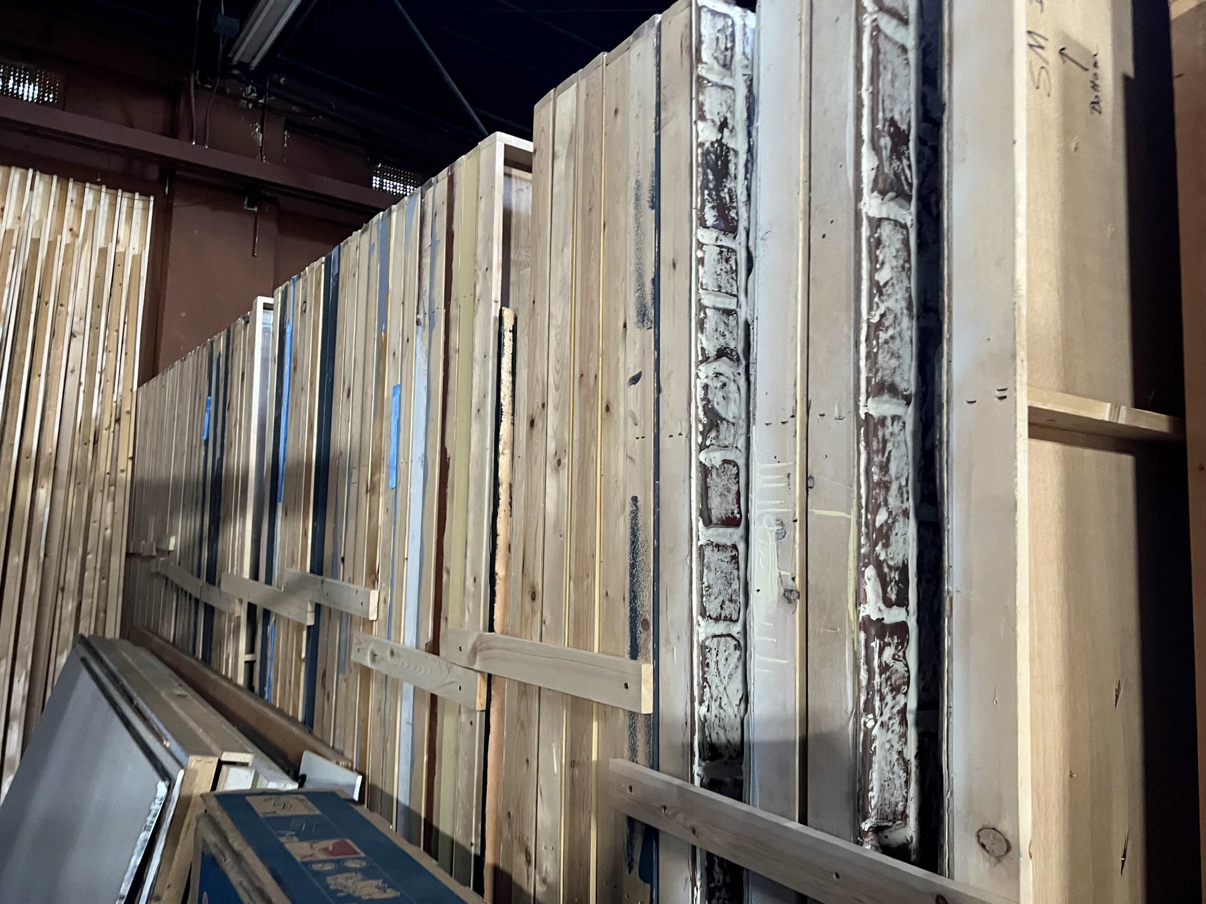 A stacked arrangement of wooden panels and framed materials in a warehouse setting.