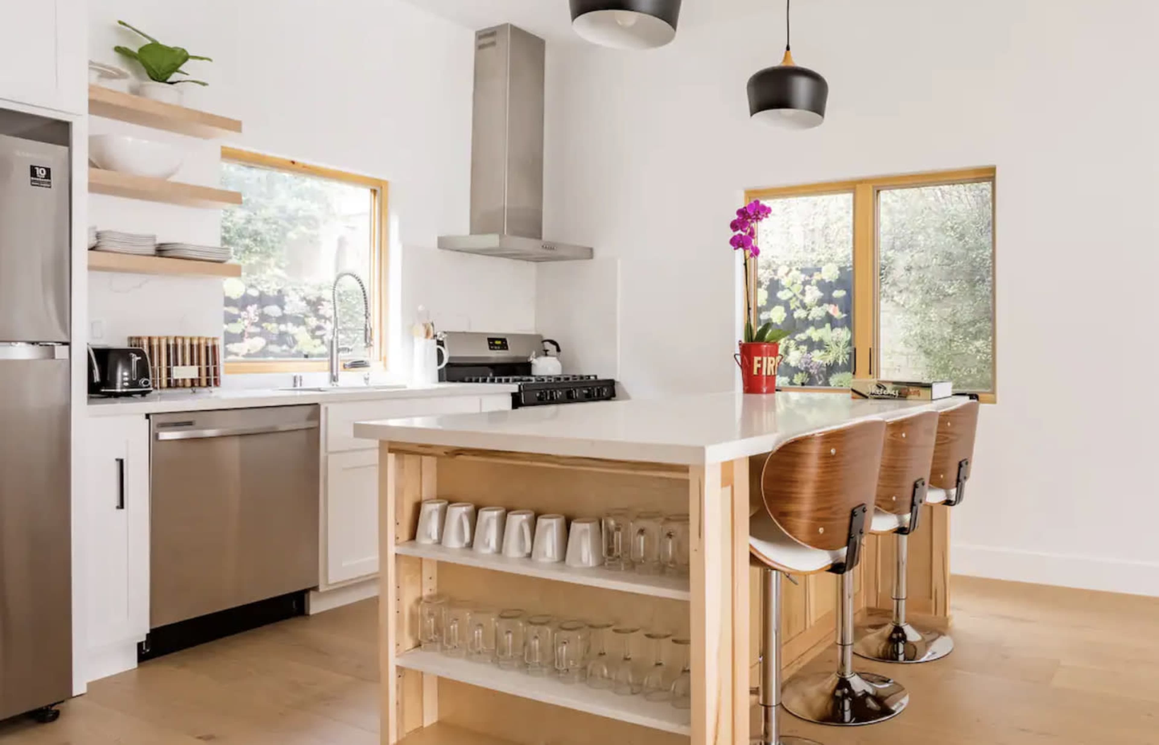 A modern kitchen with a central island that has seating, stainless steel appliances, and large windows allowing natural light.