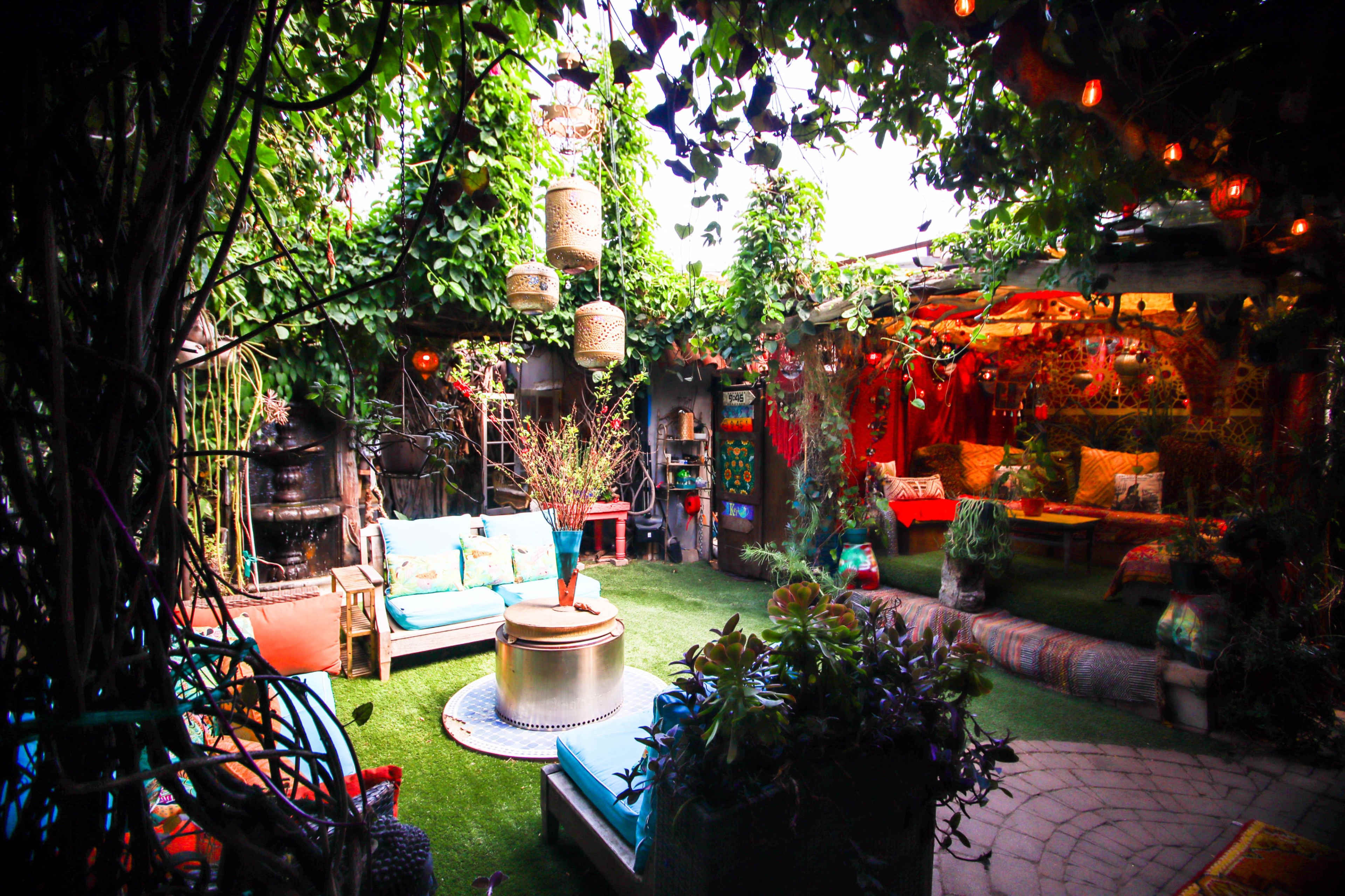 The image showcases a vibrant outdoor living area filled with lush greenery, comfortable seating, and decorative lighting.