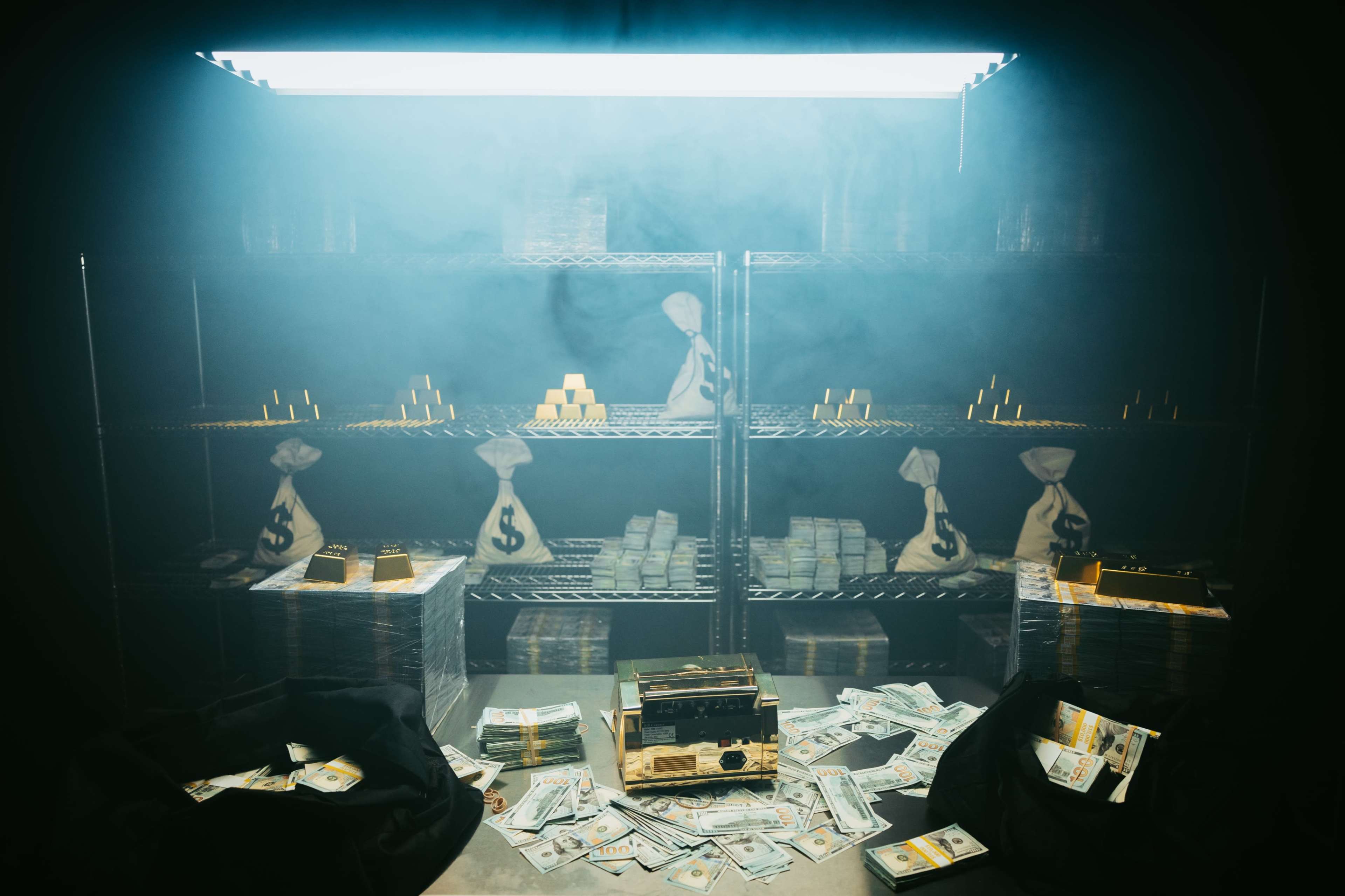 The image shows a dimly lit storage area filled with stacks of cash, gold bars, and money bags, with a foggy atmosphere.