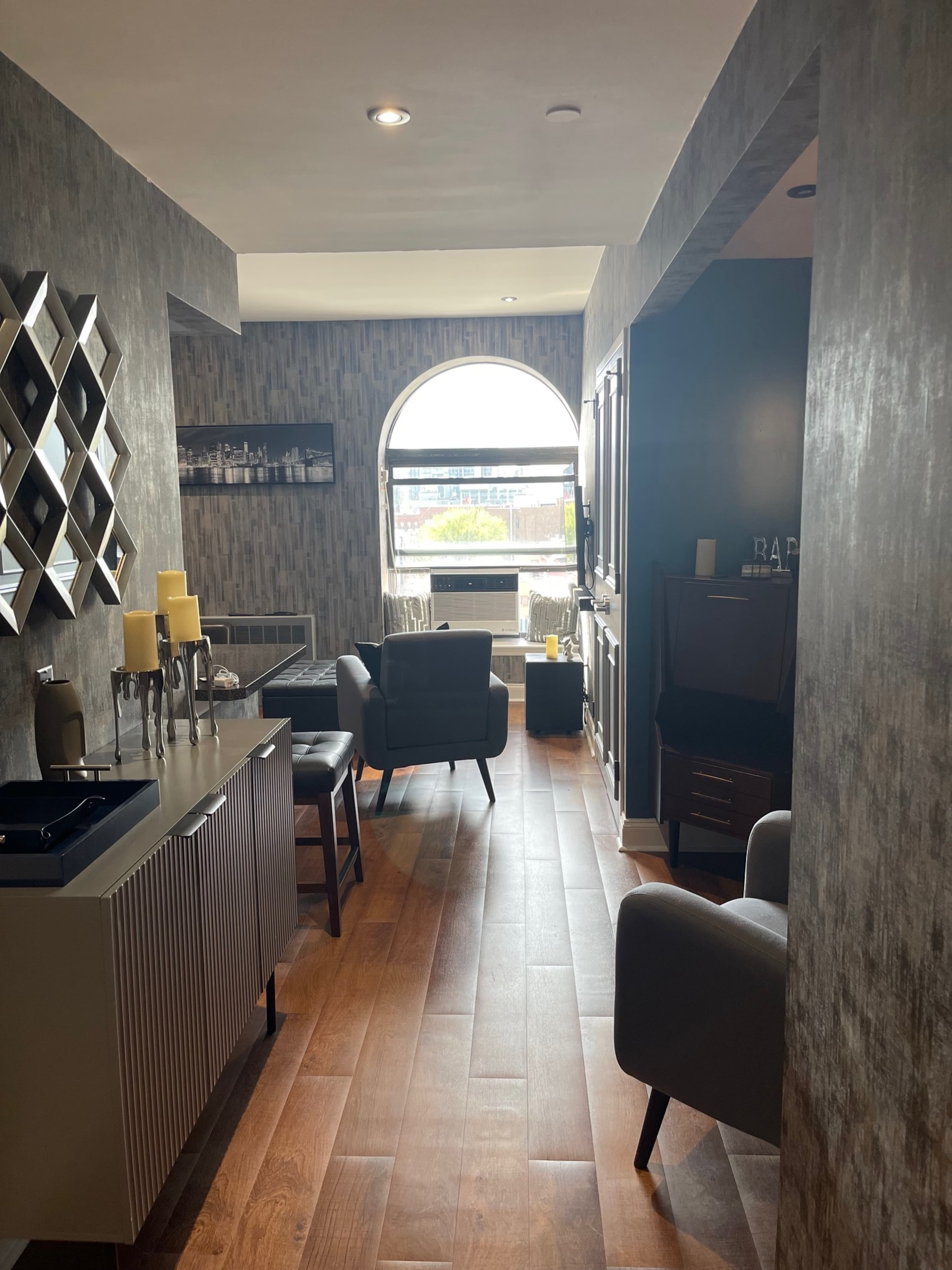 The image shows a stylish hallway leading to a window with a view, furnished with two armchairs and a side table.