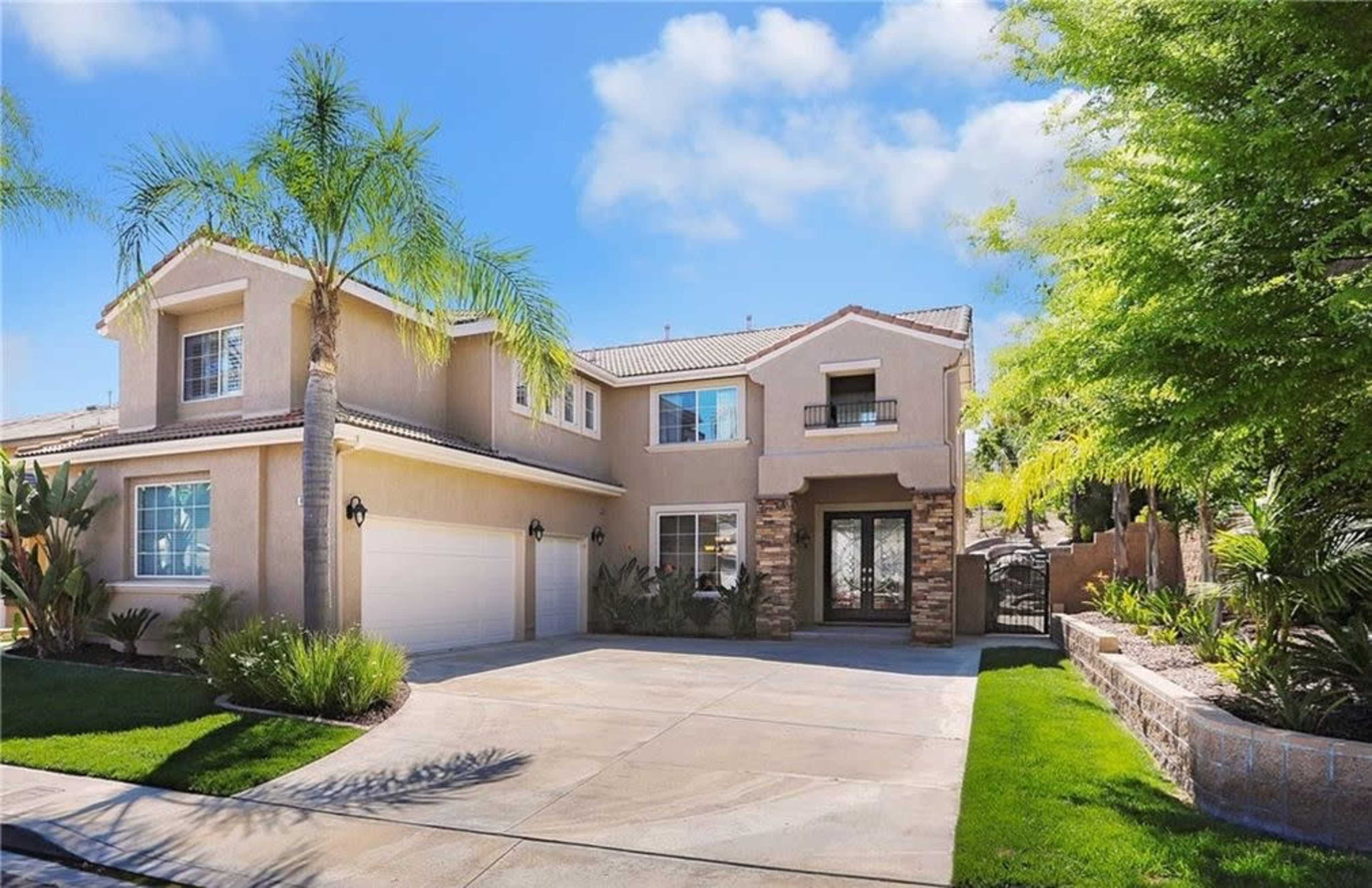 A two-story residential house with a landscaped front yard and a driveway leading to a three-car garage.
