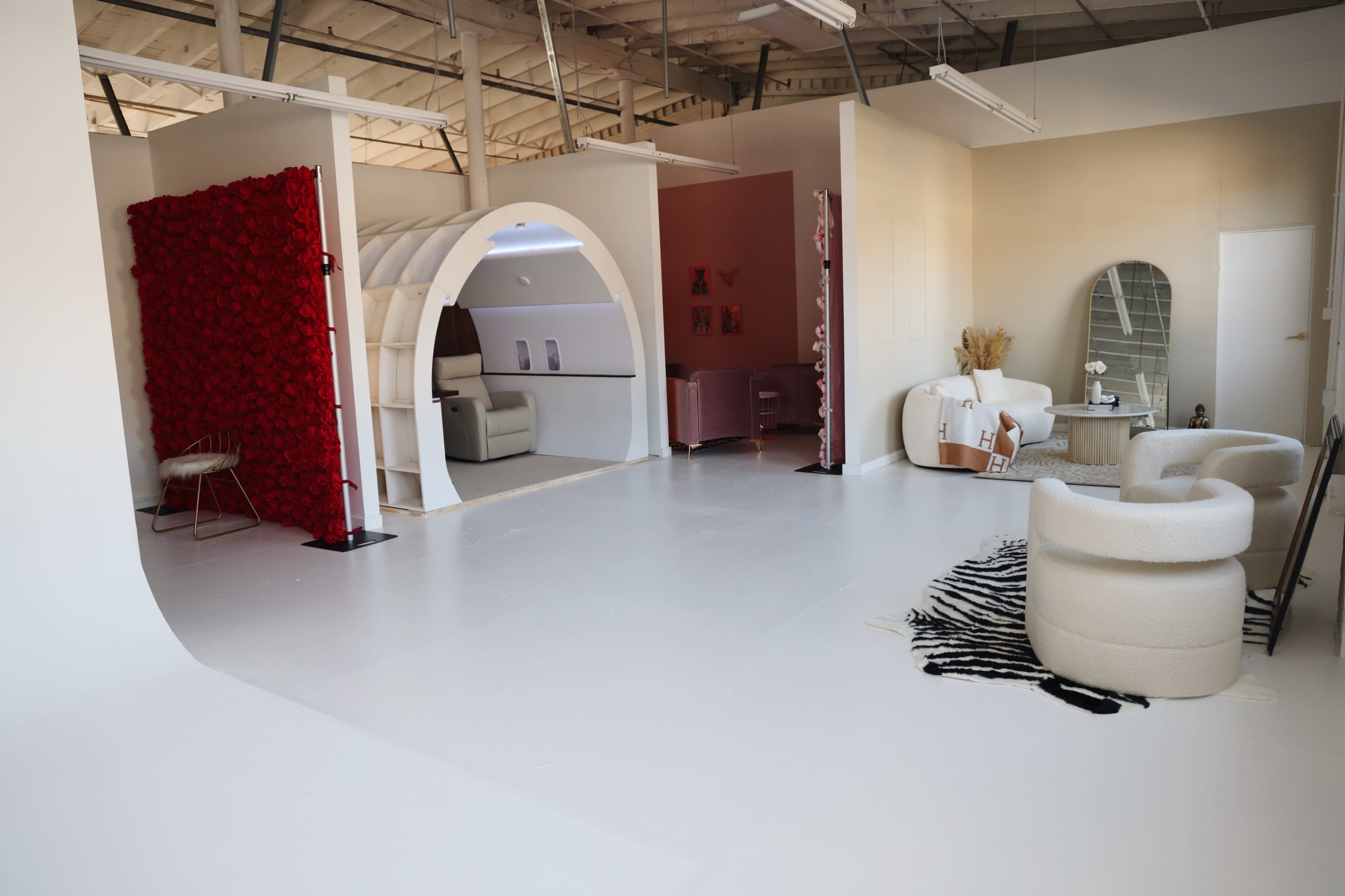 A spacious interior featuring an archway, light-colored walls, minimalist furniture, and a decorative wall with red flowers.