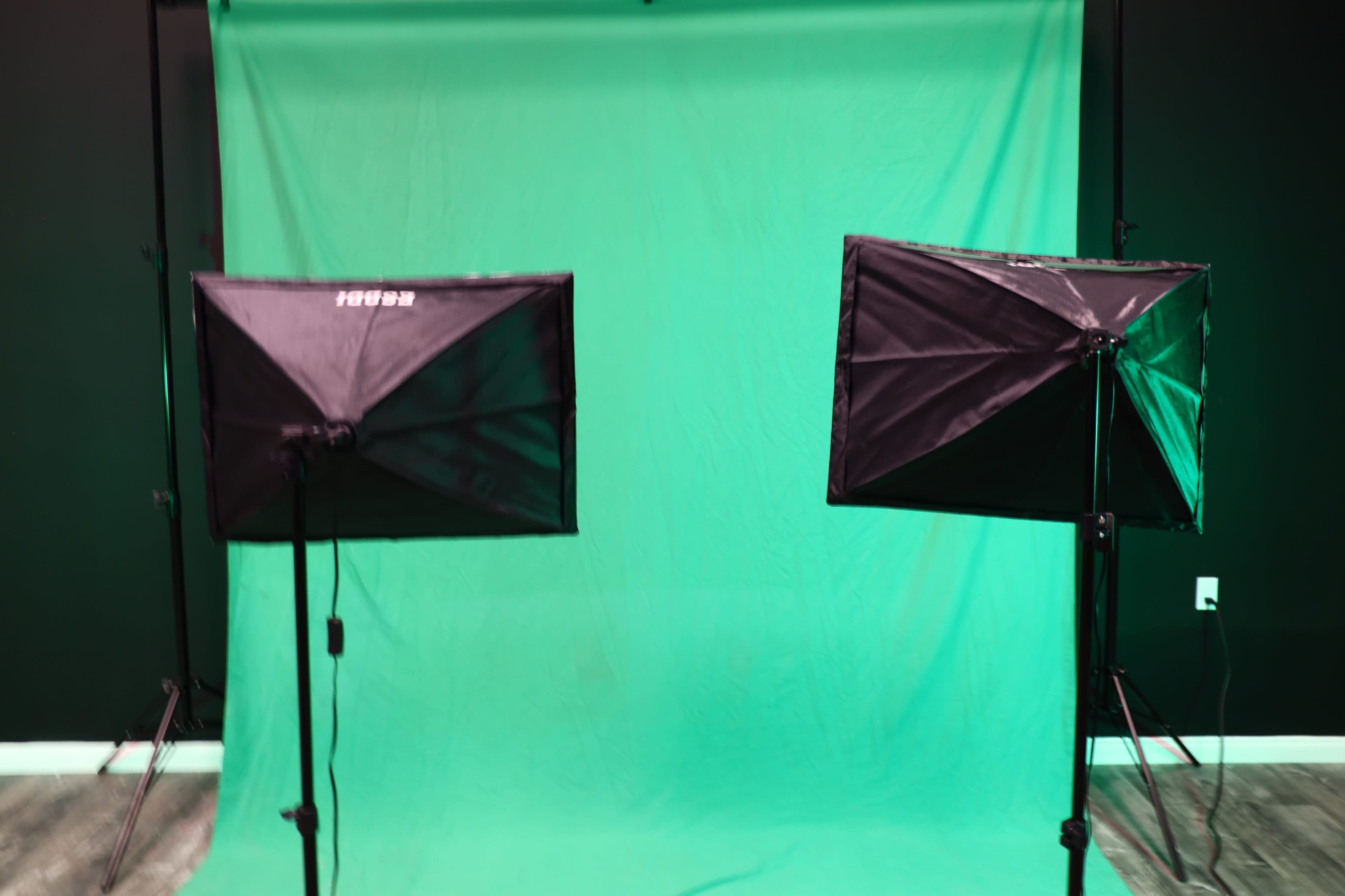 The image shows two lighting softboxes positioned on tripods in front of a green backdrop.