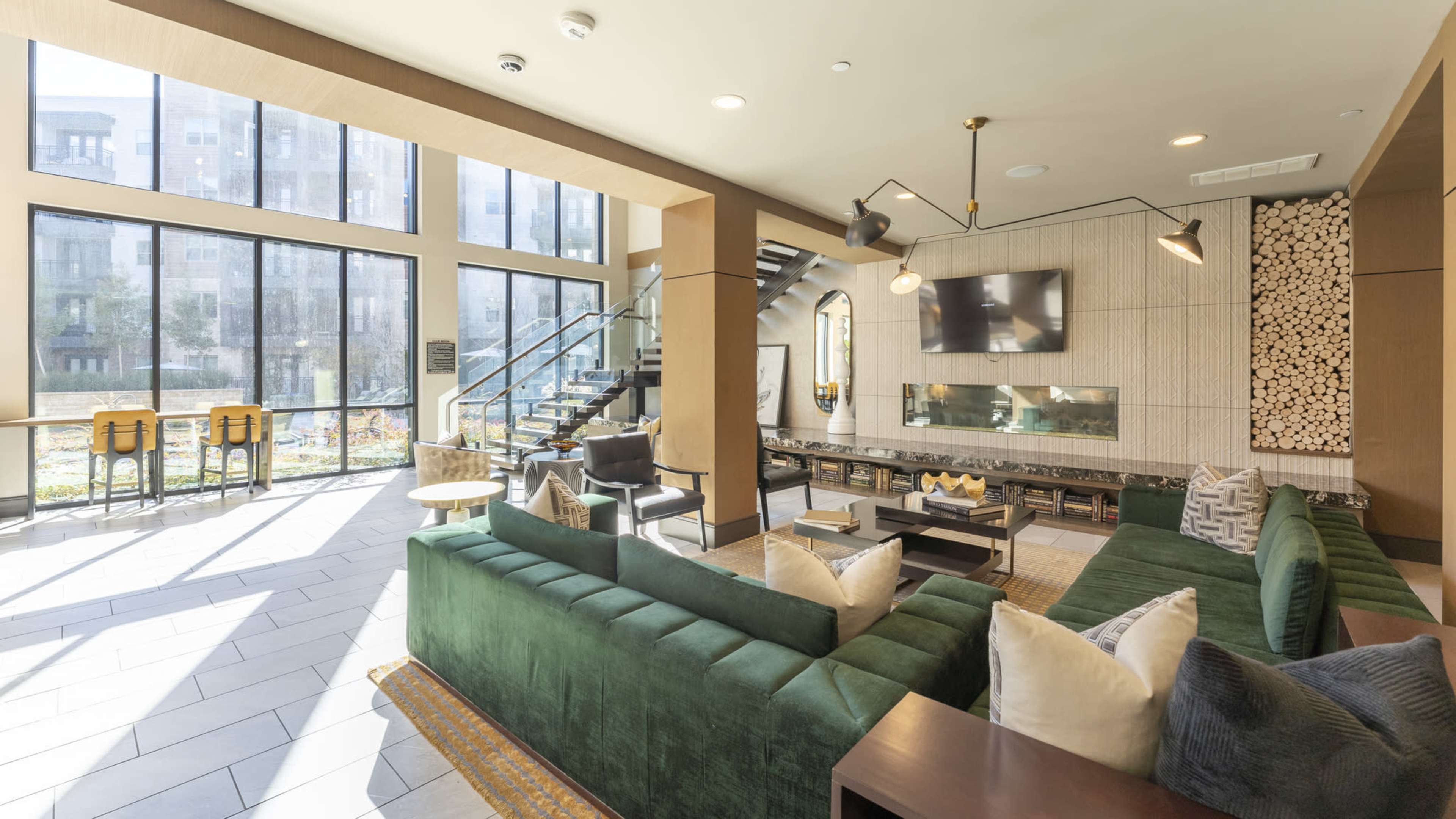 A modern lounge area with a green sectional sofa, a fireplace, and large windows that provide natural light.