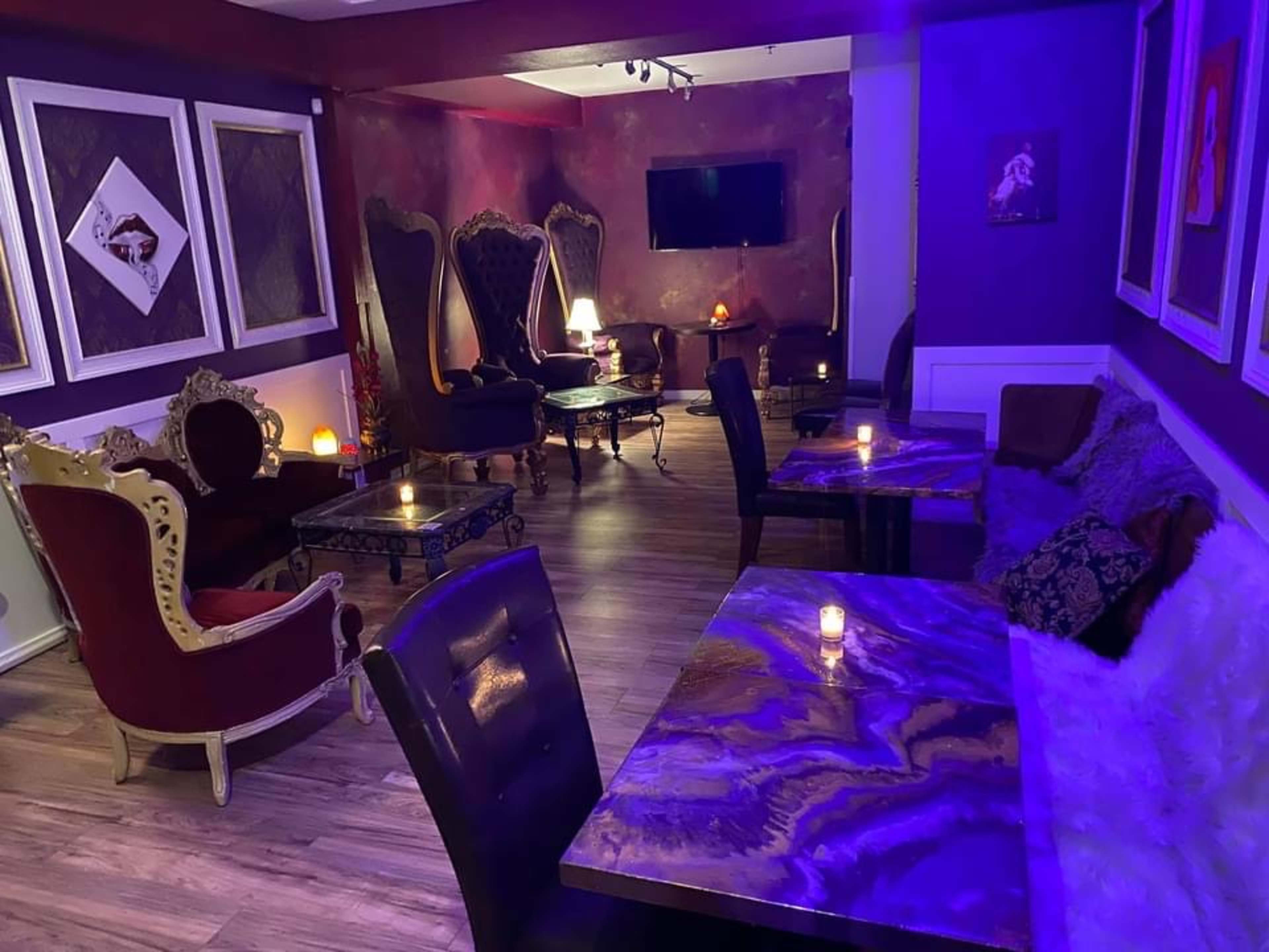 The image features a dimly lit lounge with ornate chairs and tables, illuminated by candles on each table.