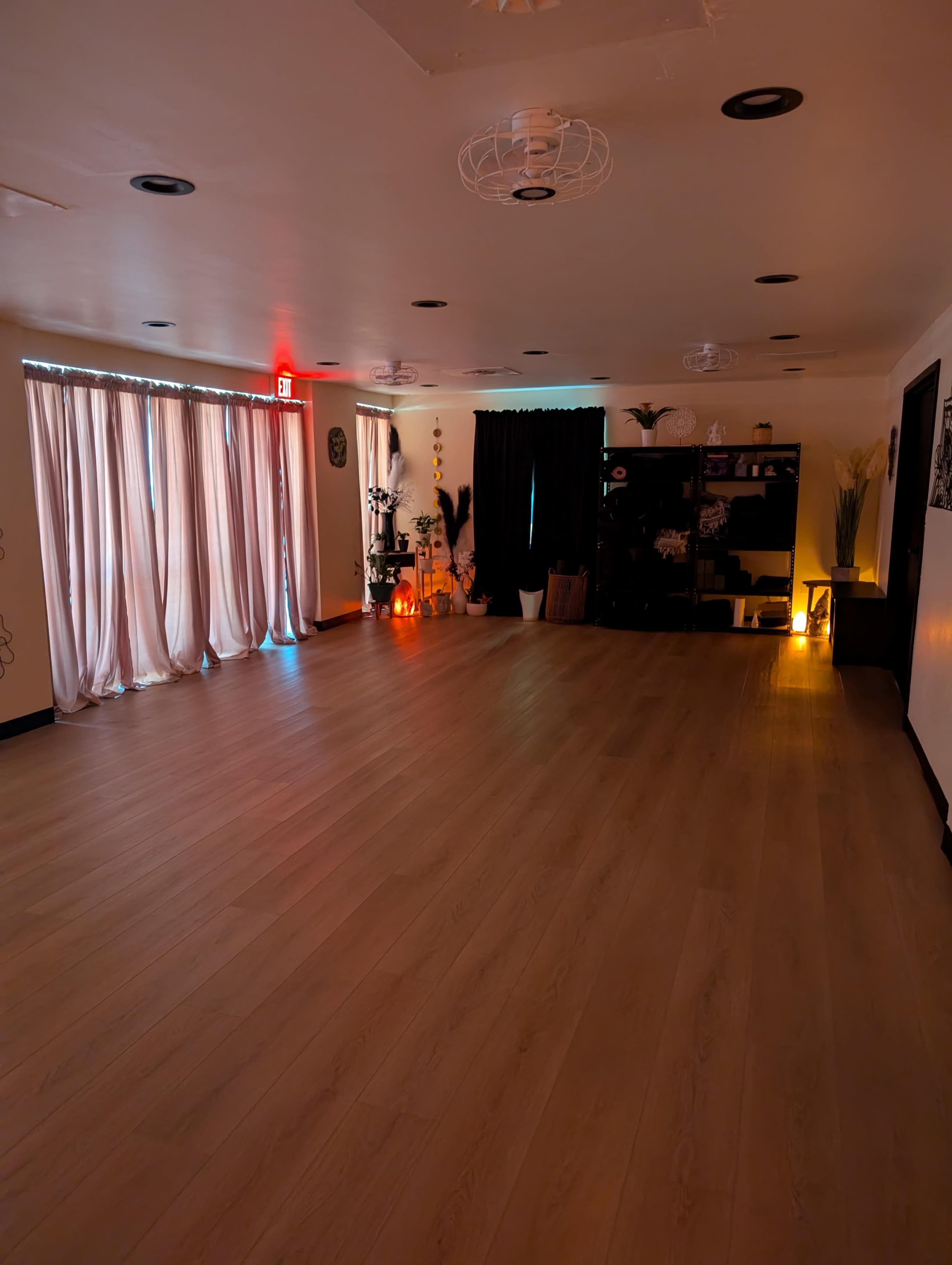 The image shows an empty studio space with wooden flooring, draped curtains, and dim lighting from various decorative sources.