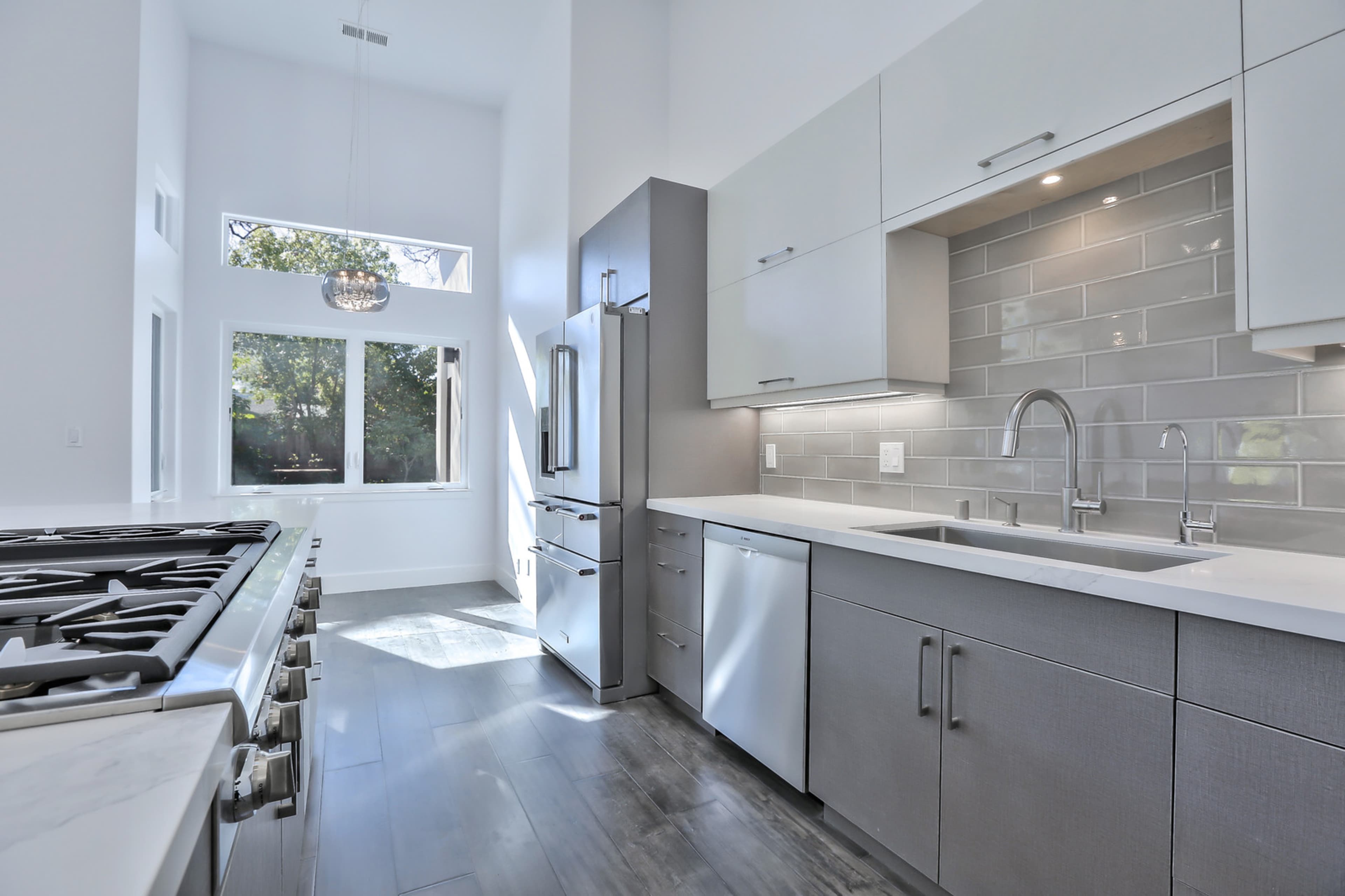 A modern kitchen with stainless steel appliances, a spacious countertop, and large windows allowing natural light to enter.