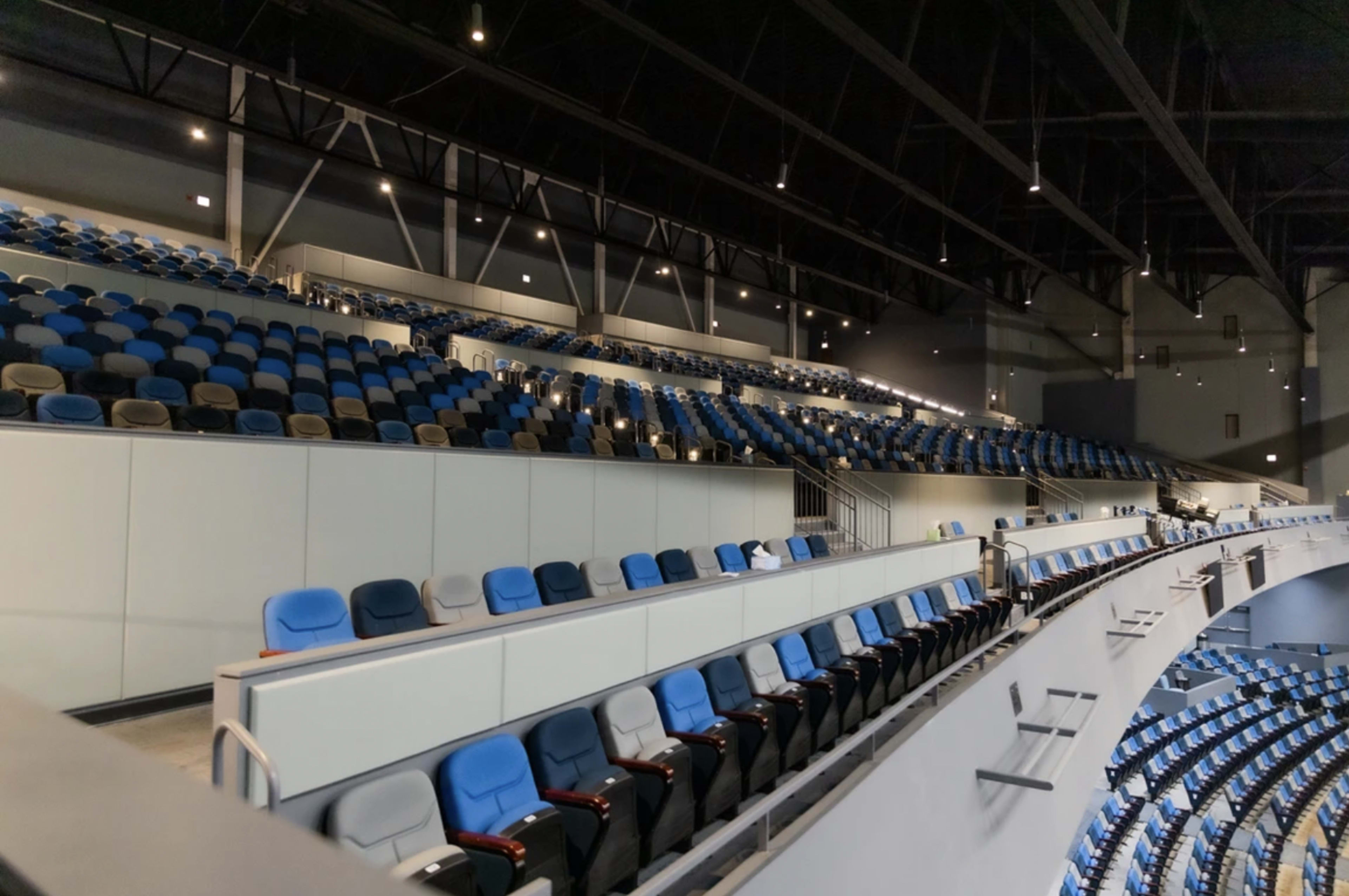 A section of an empty sports arena with tiered seating in blue and gray colors.