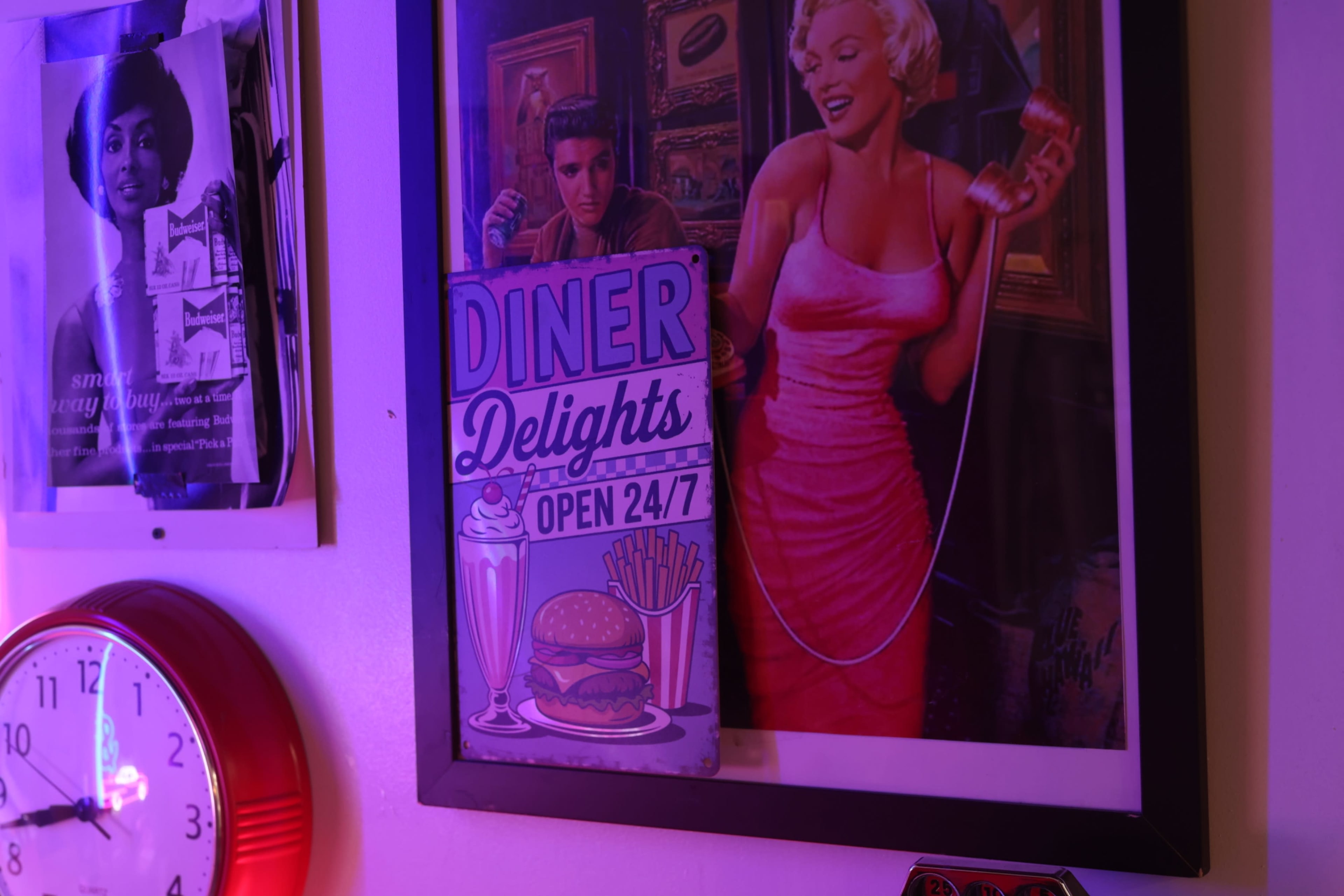 The image features a colorful diner-themed wall display with a sign reading "Diner Delights - Open 24/7" alongside a vintage-style portrait of a smiling woman in a pink dress and a man holding a drink.