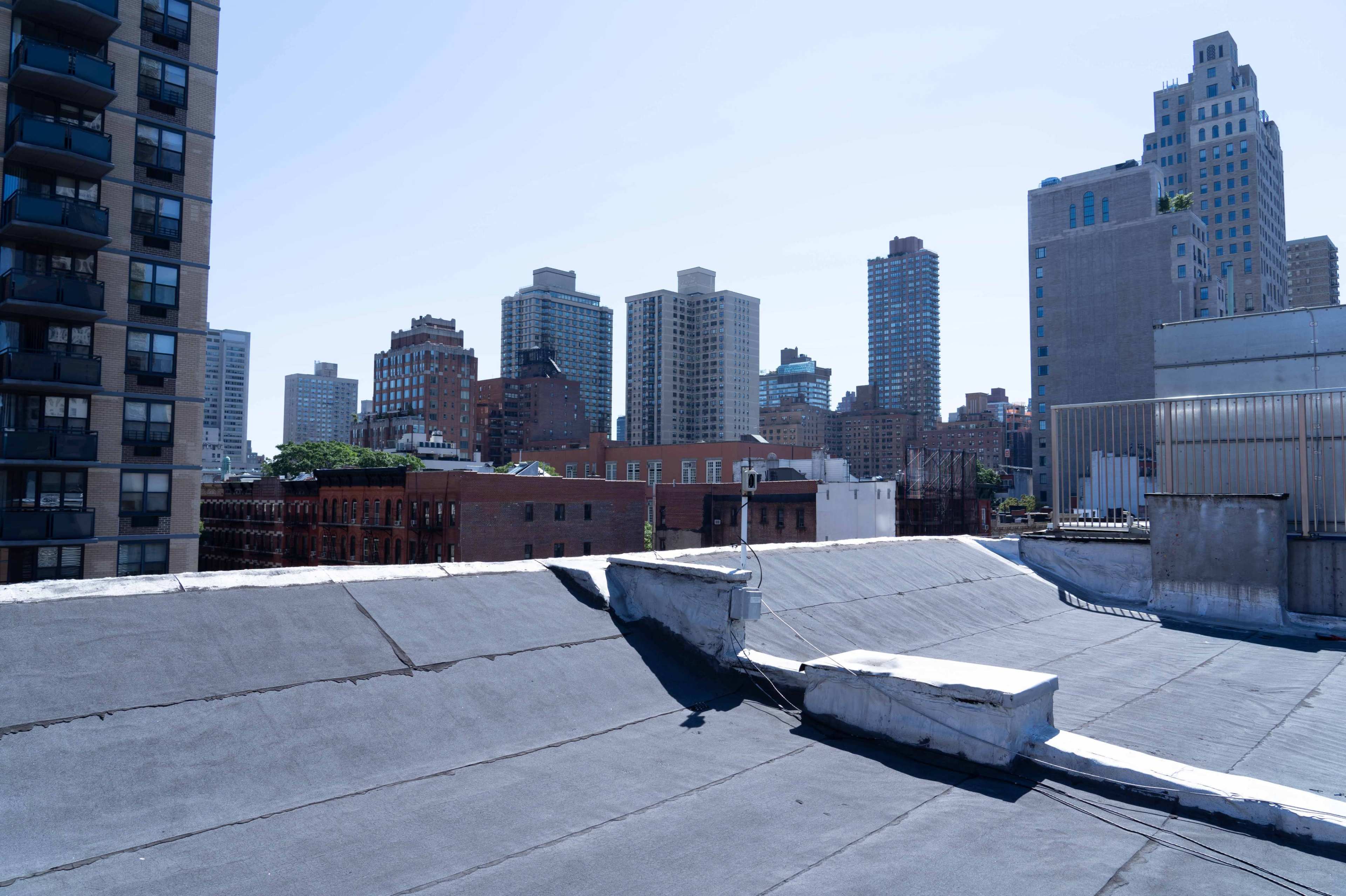 A rooftop view of a city skyline with tall buildings in the background under a clear blue sky.