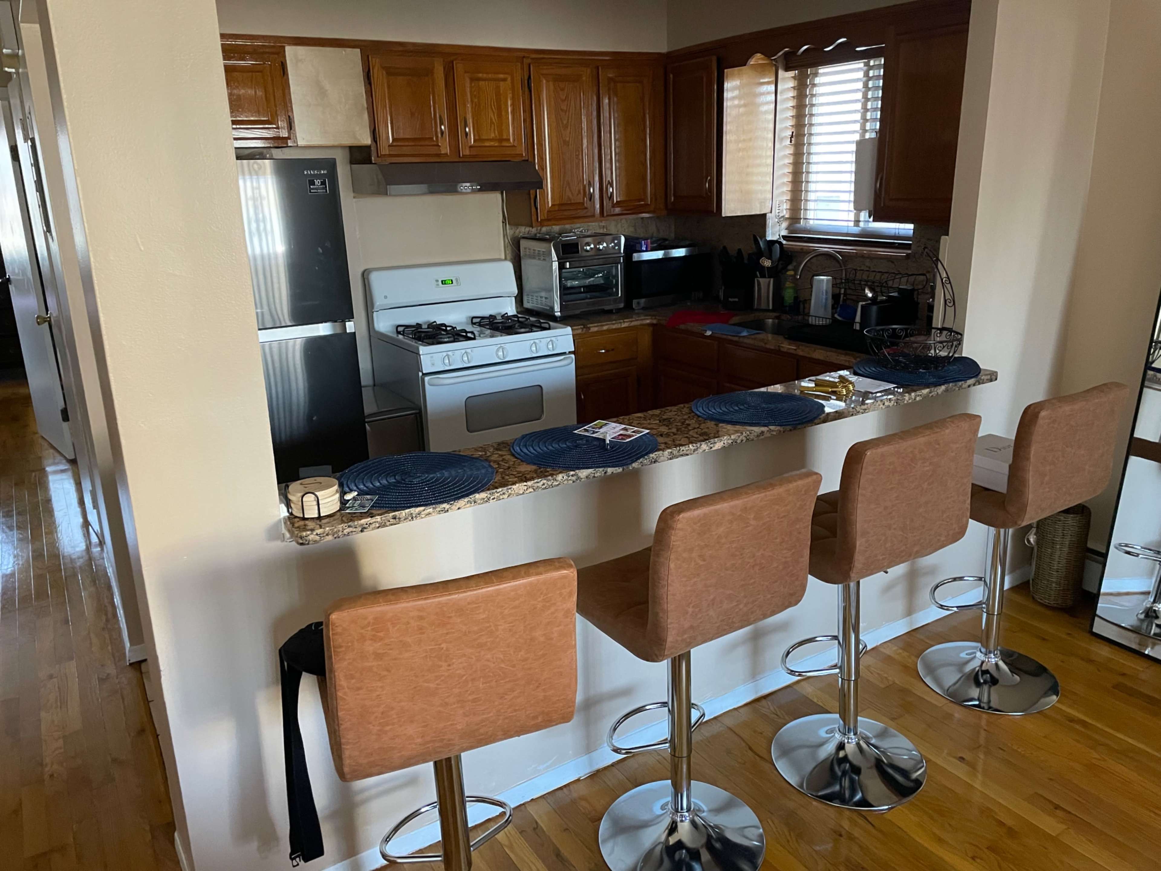 A kitchen features wooden cabinetry, a gas stove, and a breakfast bar with four stools.