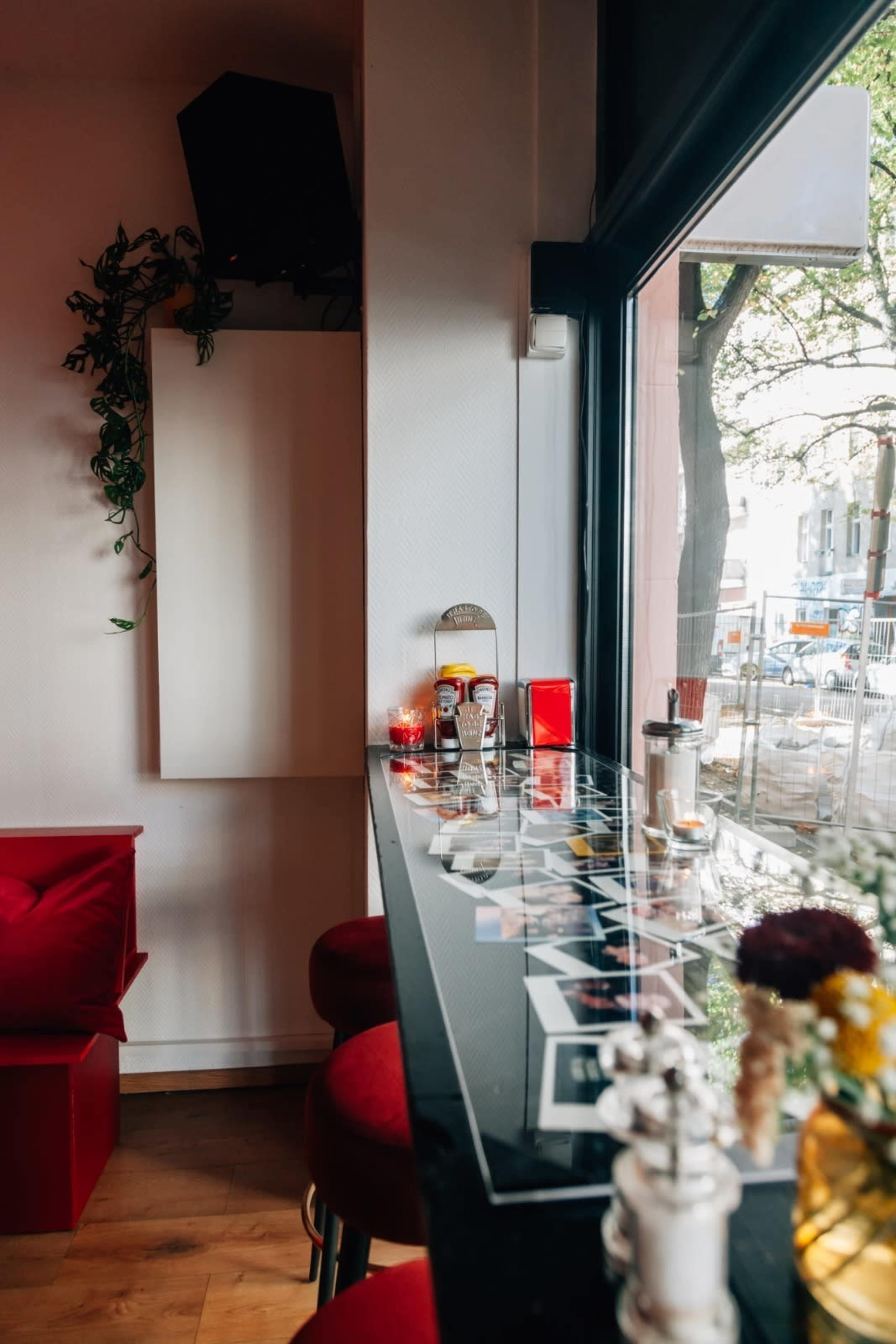 A cozy bar area features a glass countertop adorned with decorative items and condiments, next to a window with views of the street outside.