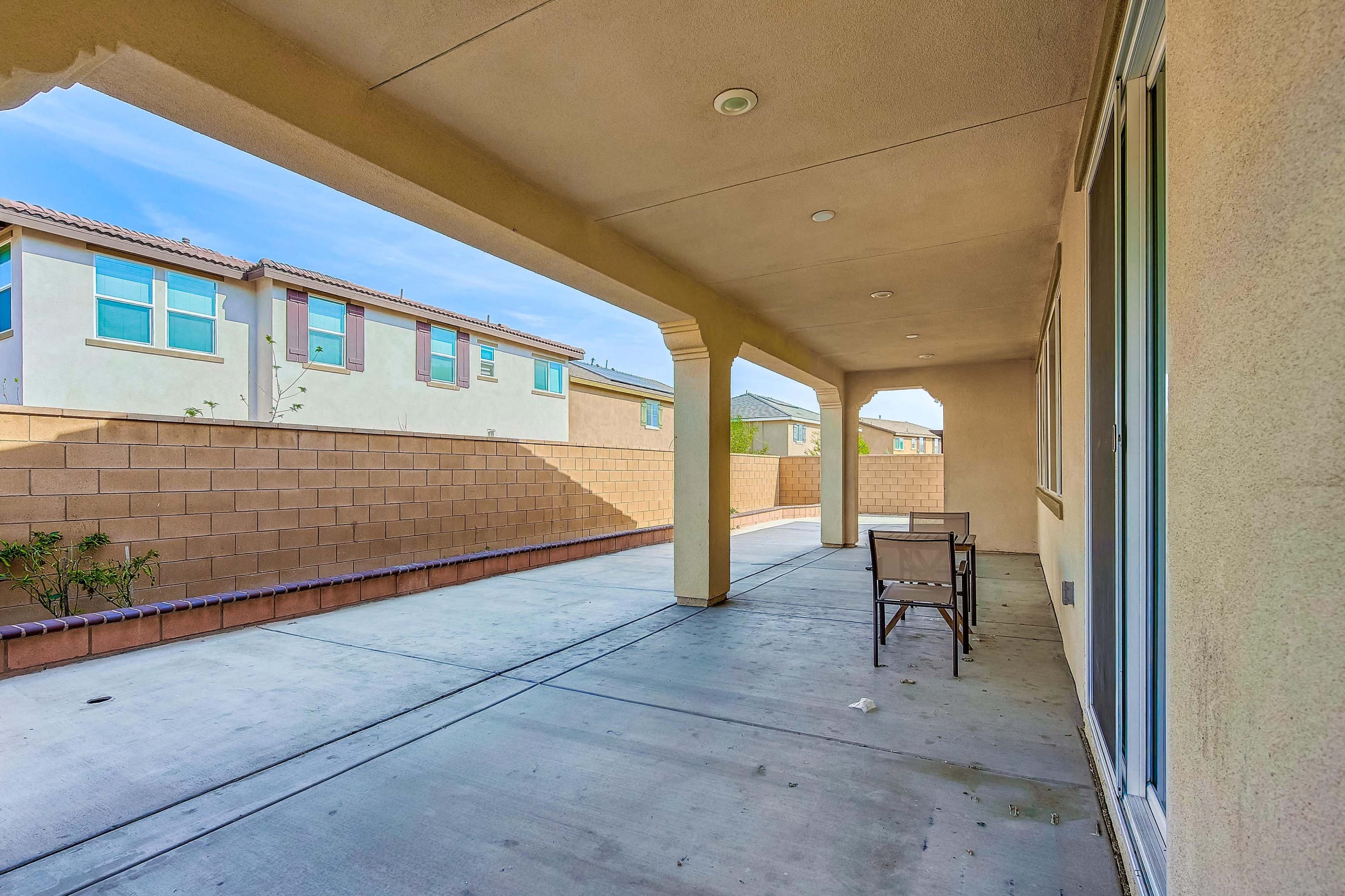 A covered patio area adjacent to a wall with neighboring houses visible in the background.