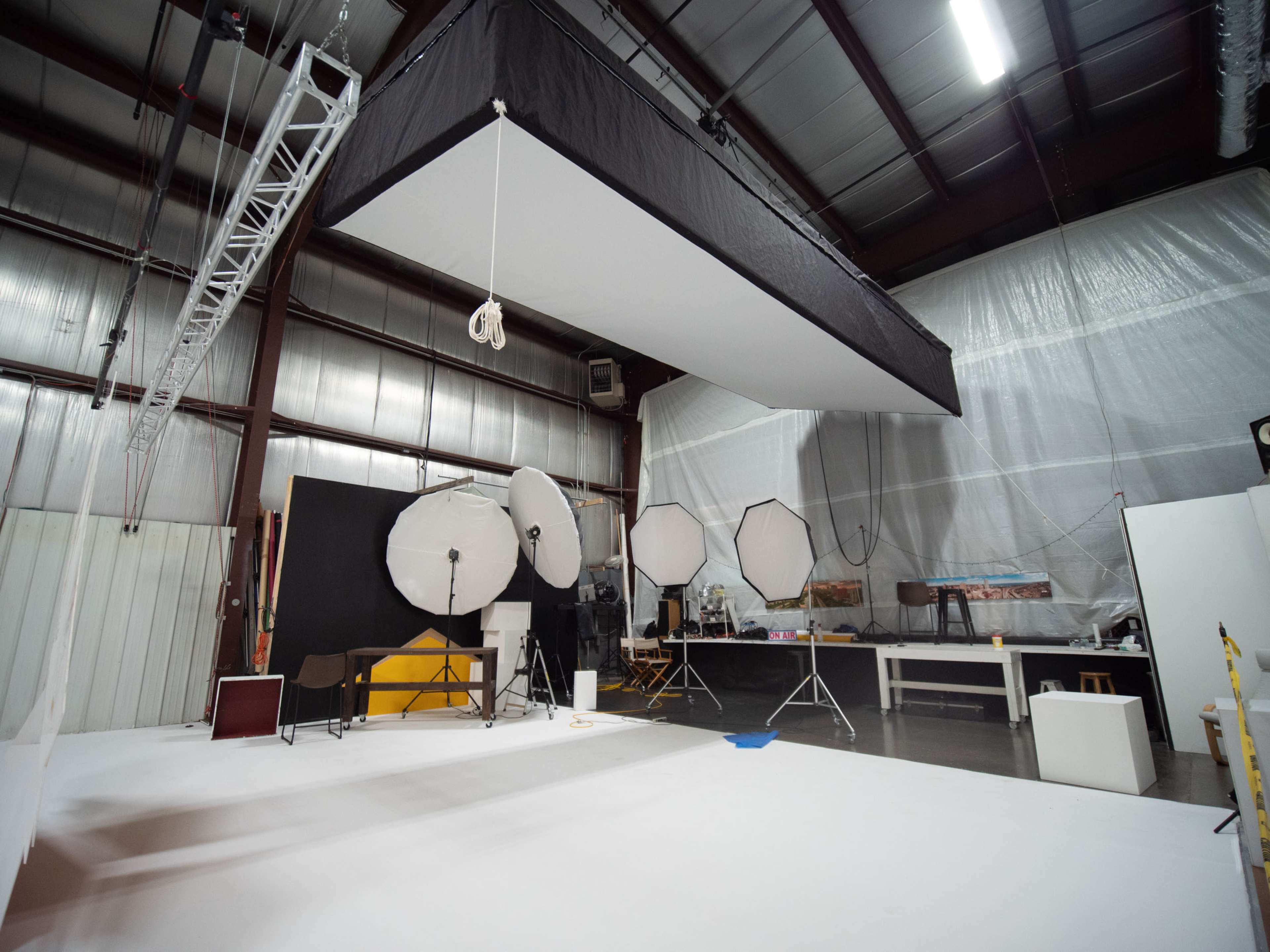 A photography studio equipped with several large softbox lights, a white backdrop, and various pieces of studio equipment.