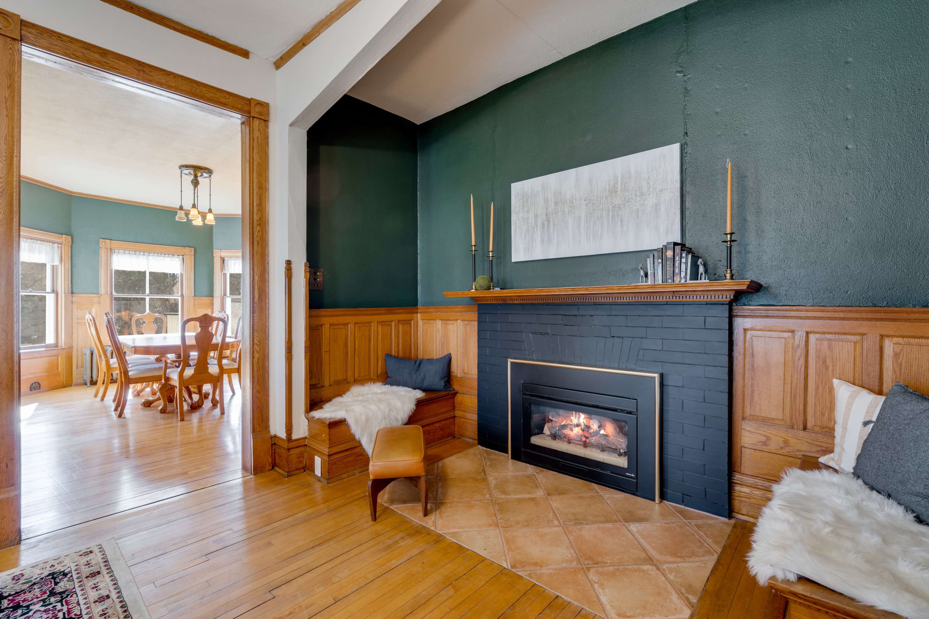 A cozy living space featuring a black fireplace, wooden paneling, and a dining area visible through an open doorway.
