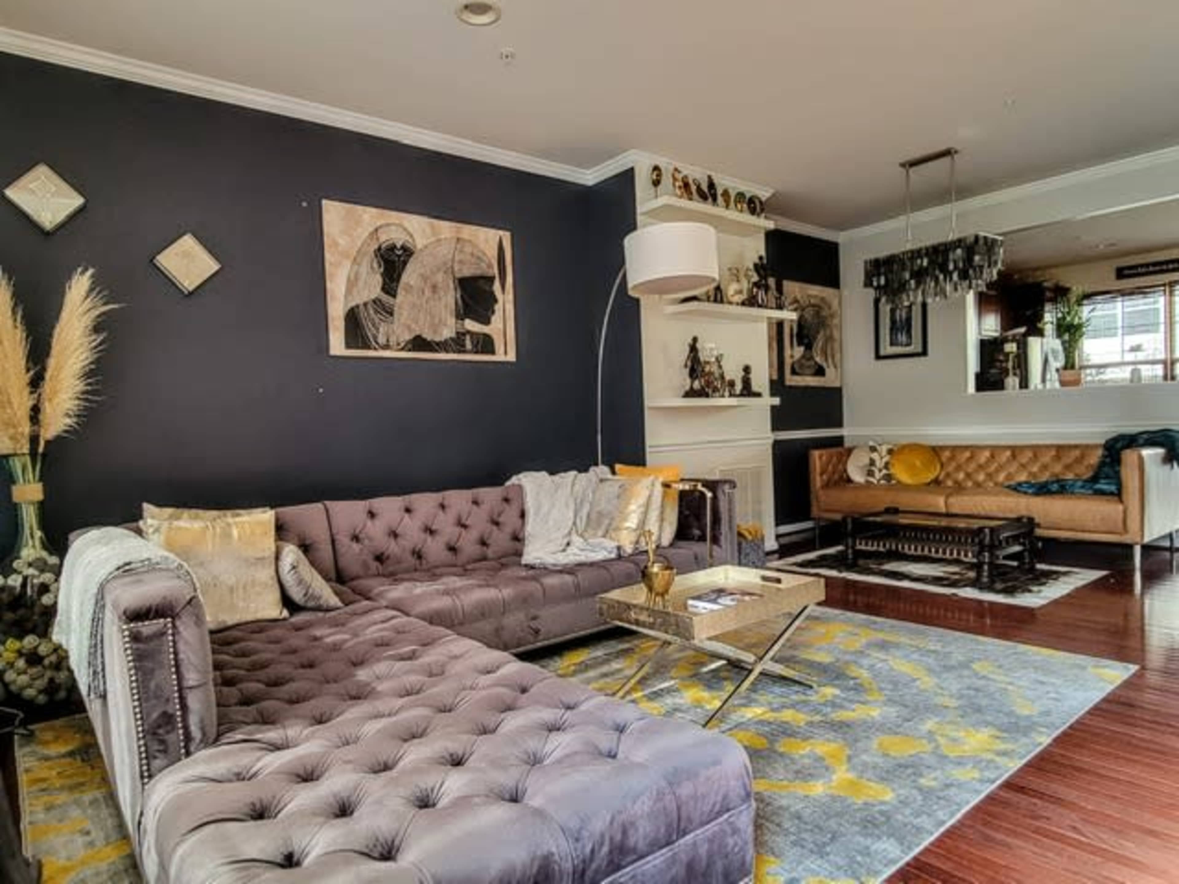 A stylish living room featuring a dark accent wall, two sofas, a coffee table, and various decorative items, all arranged to create a cozy atmosphere.