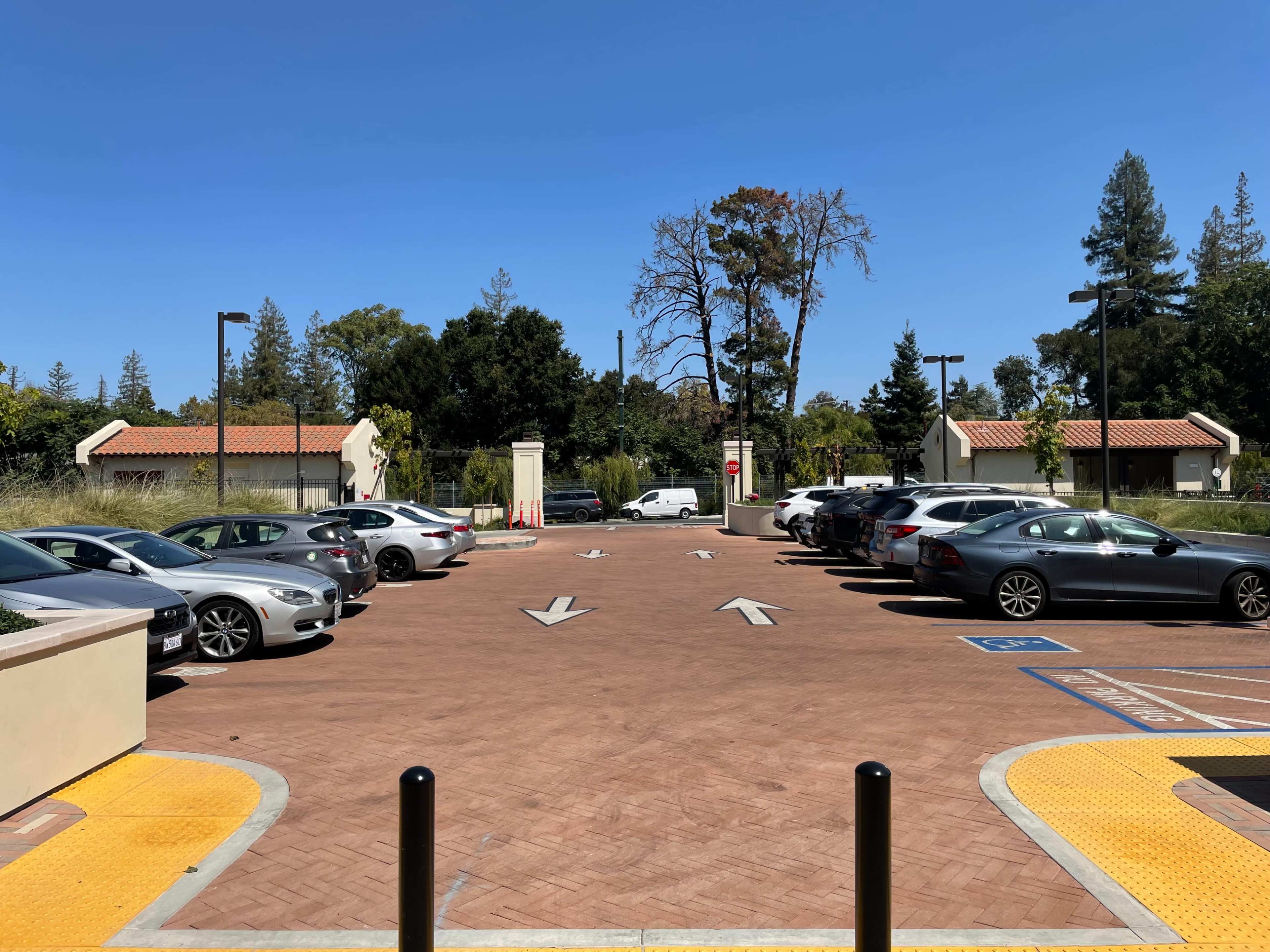 A parking area with parked cars on either side of a central lane marked by directional arrows.