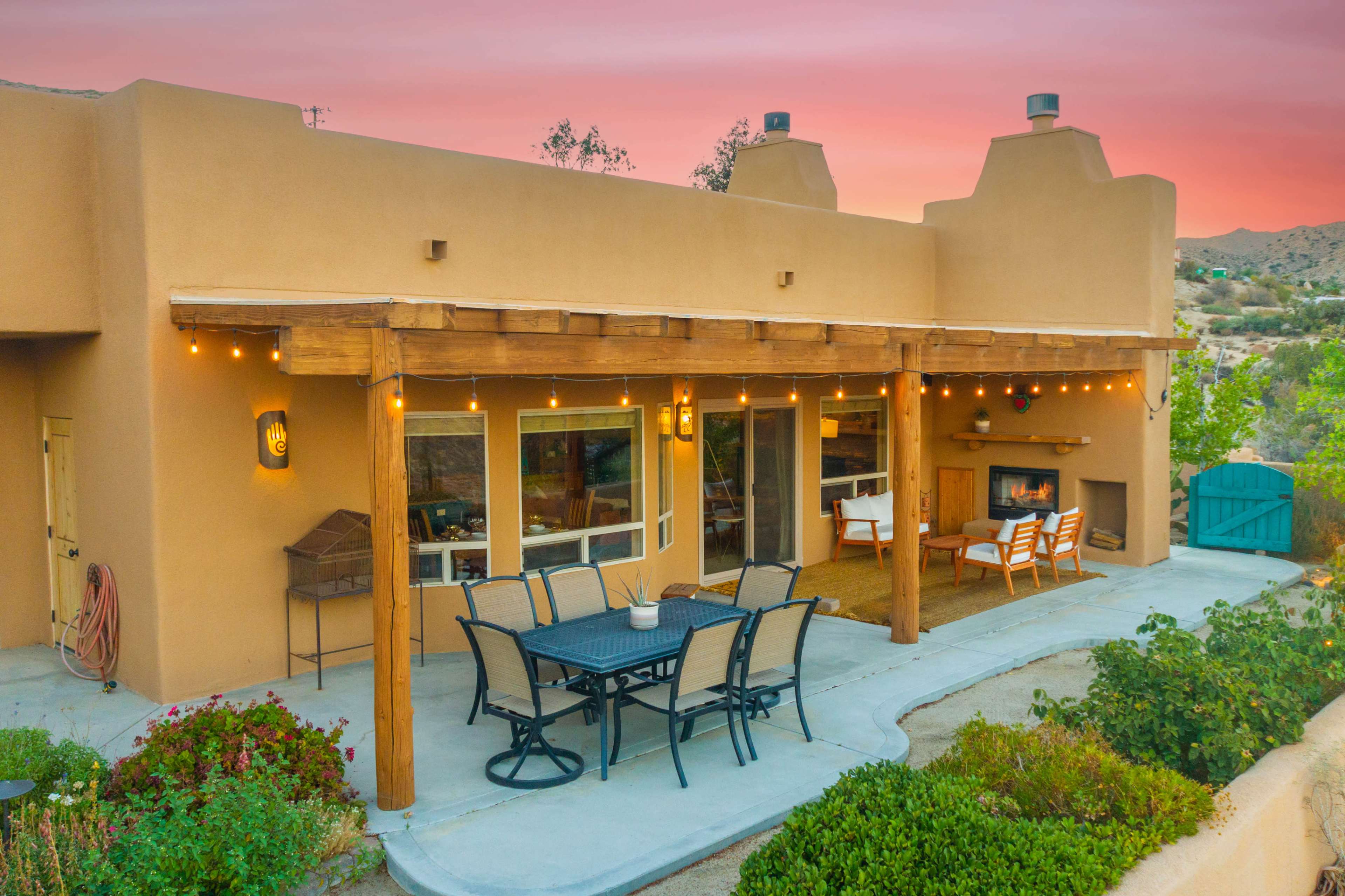 A southwestern-style home features a covered patio with a dining table and chairs, surrounded by desert landscaping.