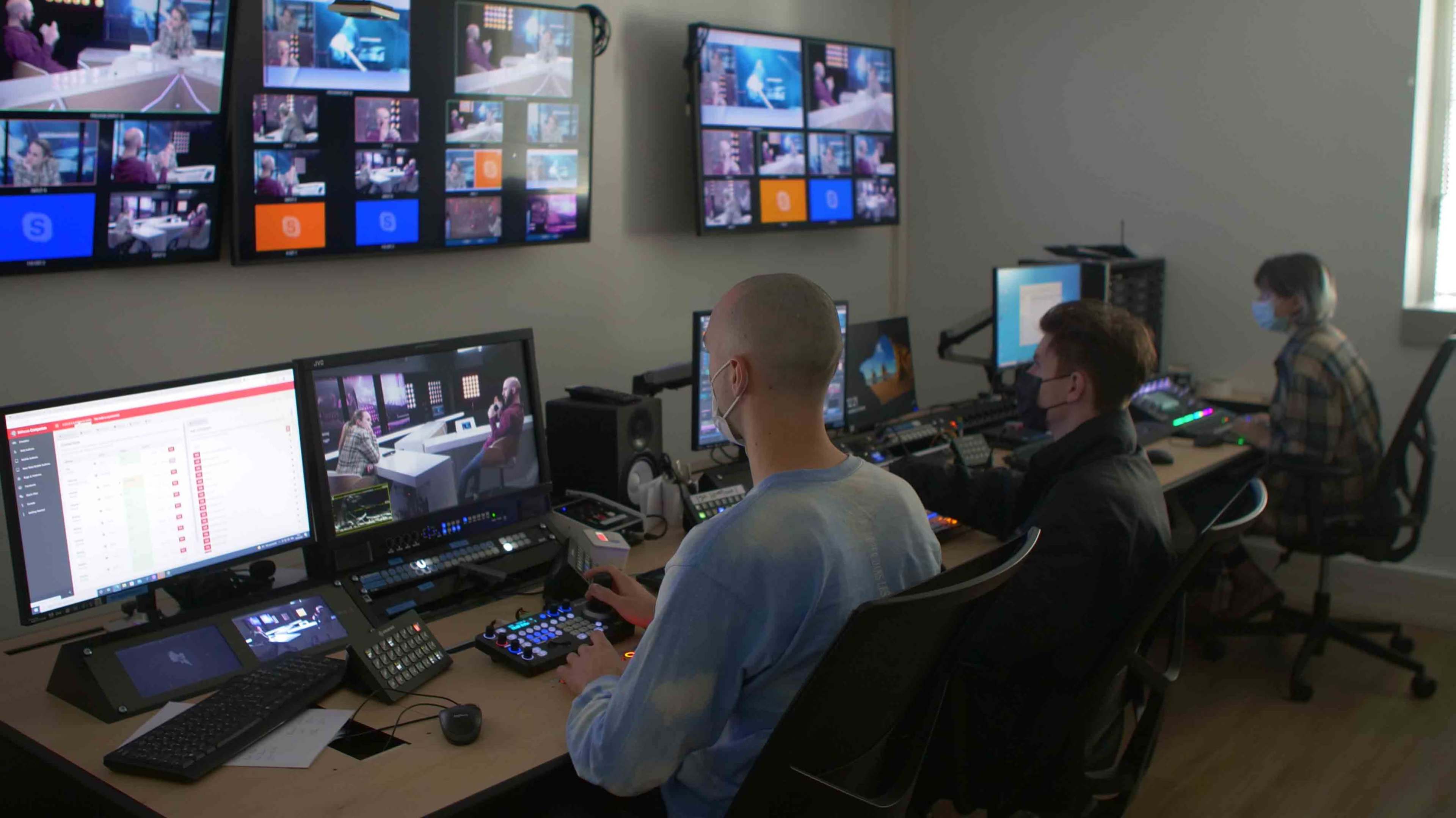 A control room with multiple monitors displaying video feeds, where operators are managing a live broadcast.