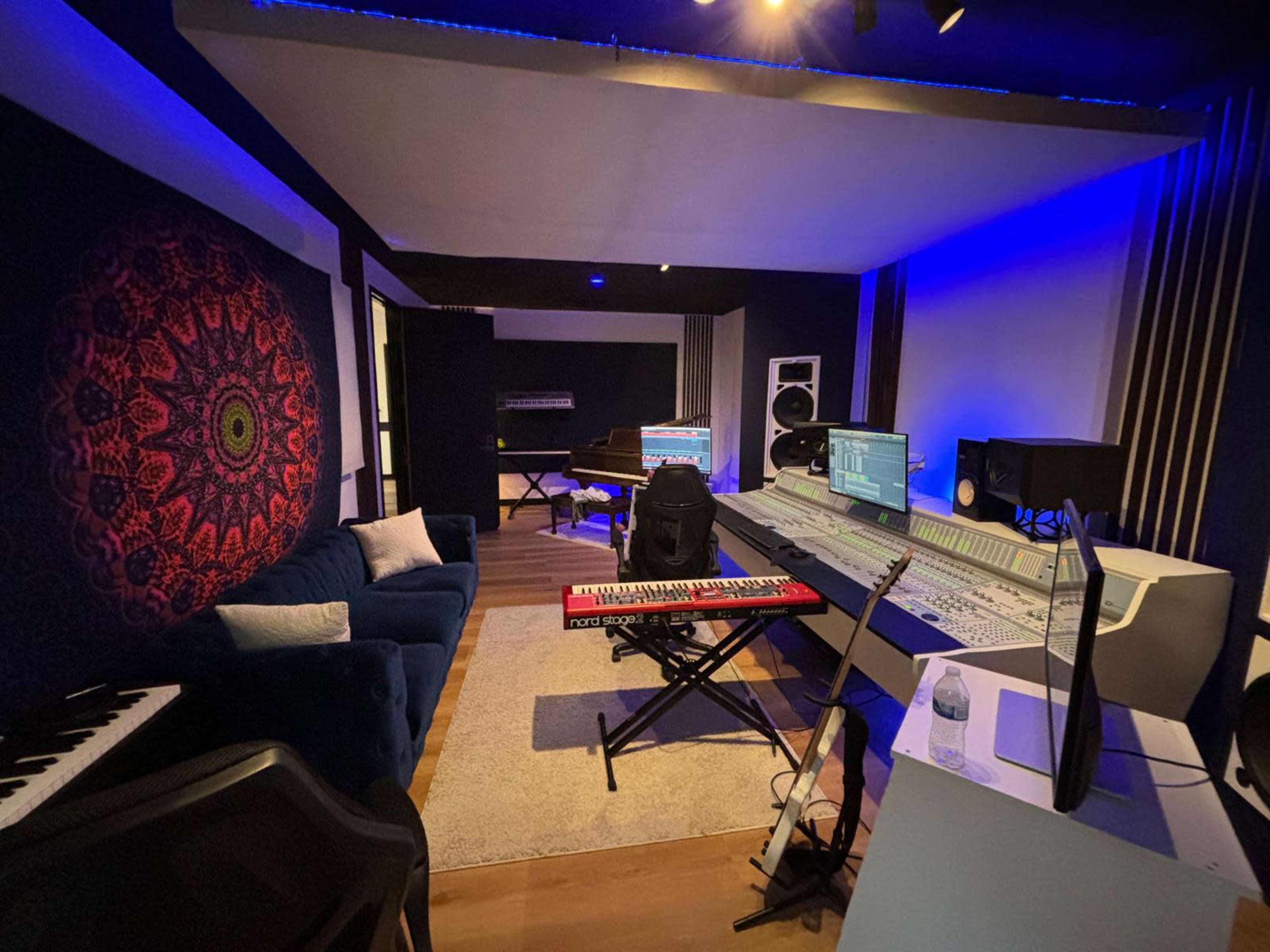 A modern music studio featuring a mixing console, various instruments, and ambient lighting.