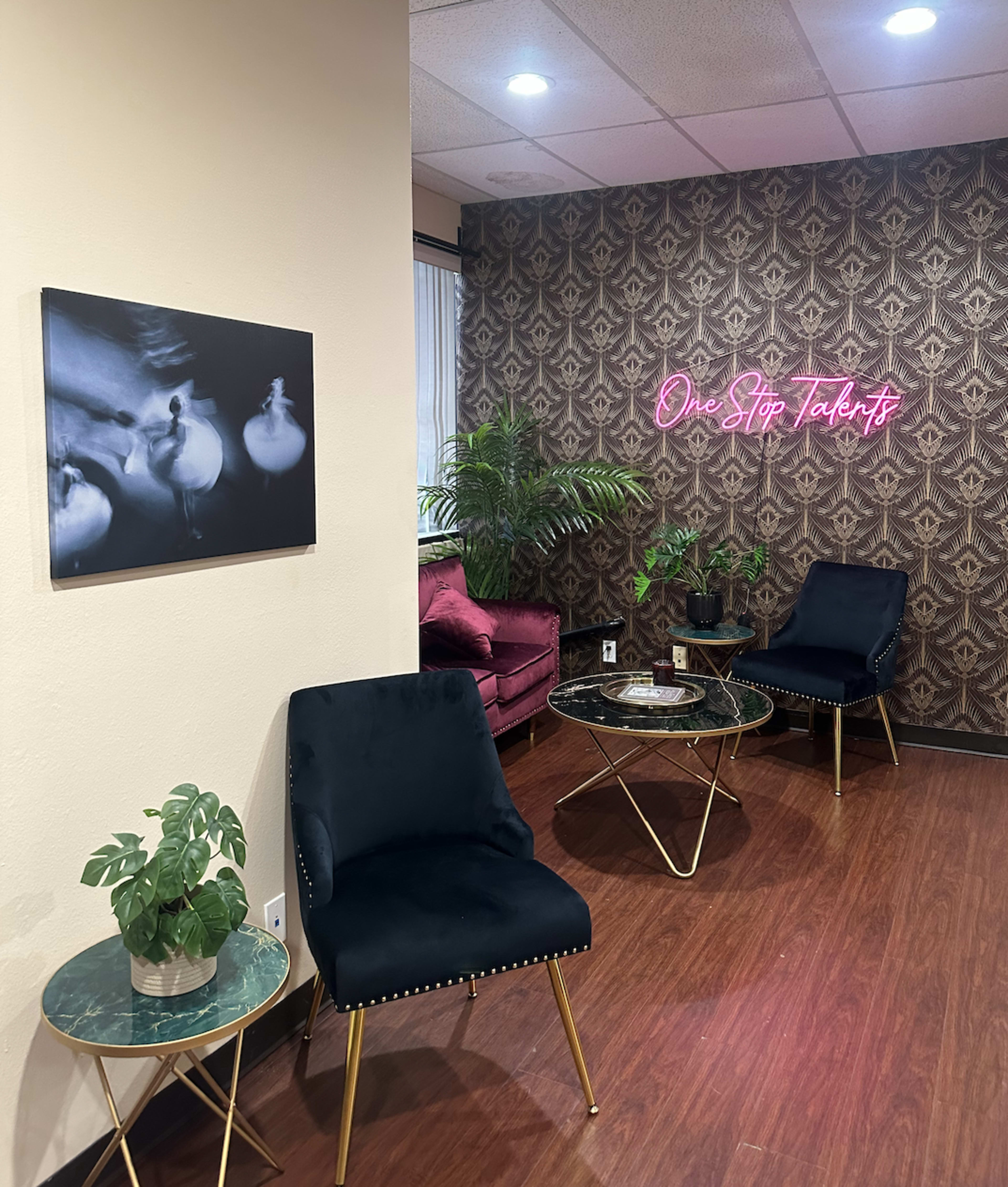 A modern interior with dark chairs, a small plant, and neon signage against a patterned wall.