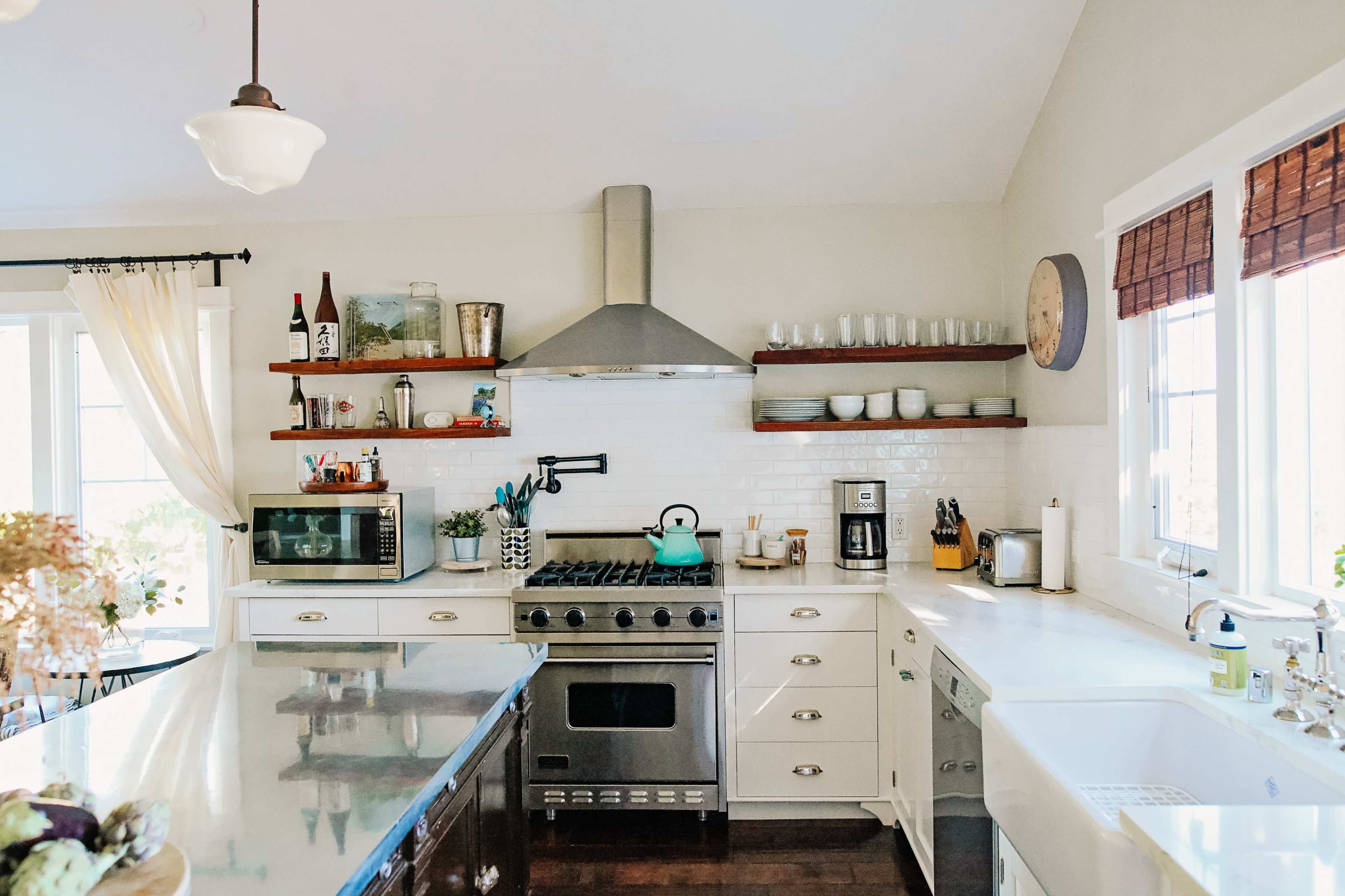 A modern kitchen features stainless steel appliances, open shelves with decorative items, and a large island with dark countertops.