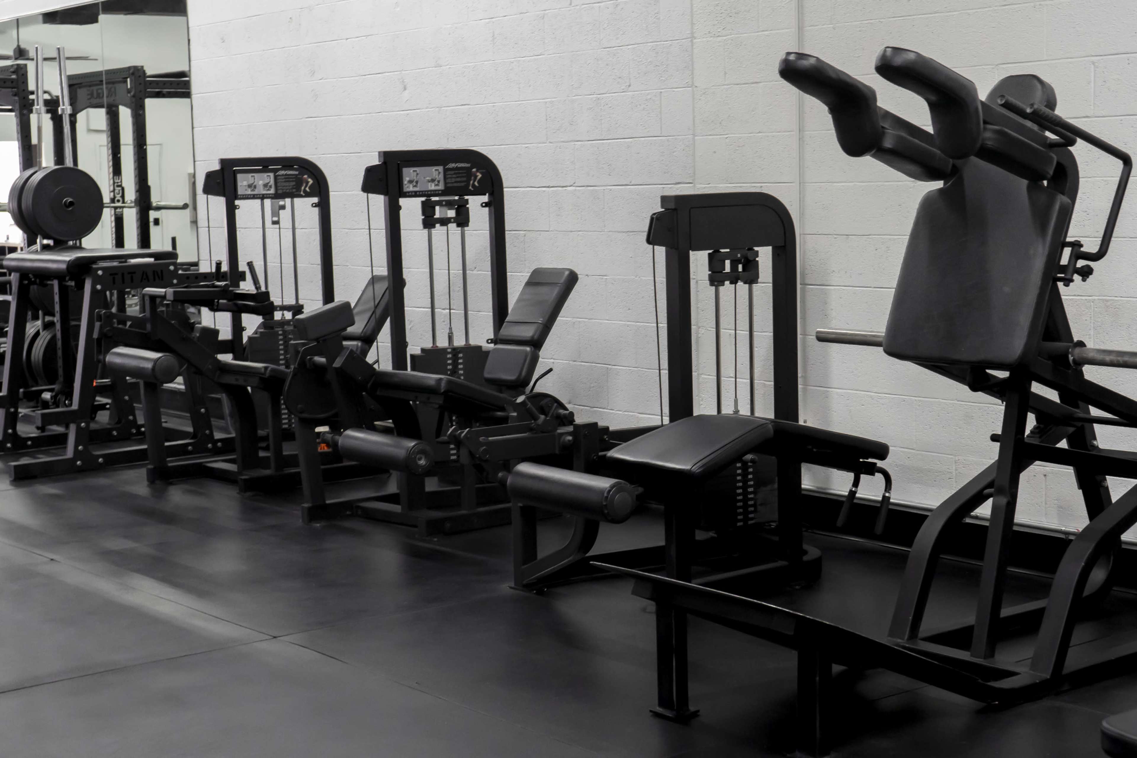 The image shows a row of black gym equipment lined against a wall in a fitness facility.