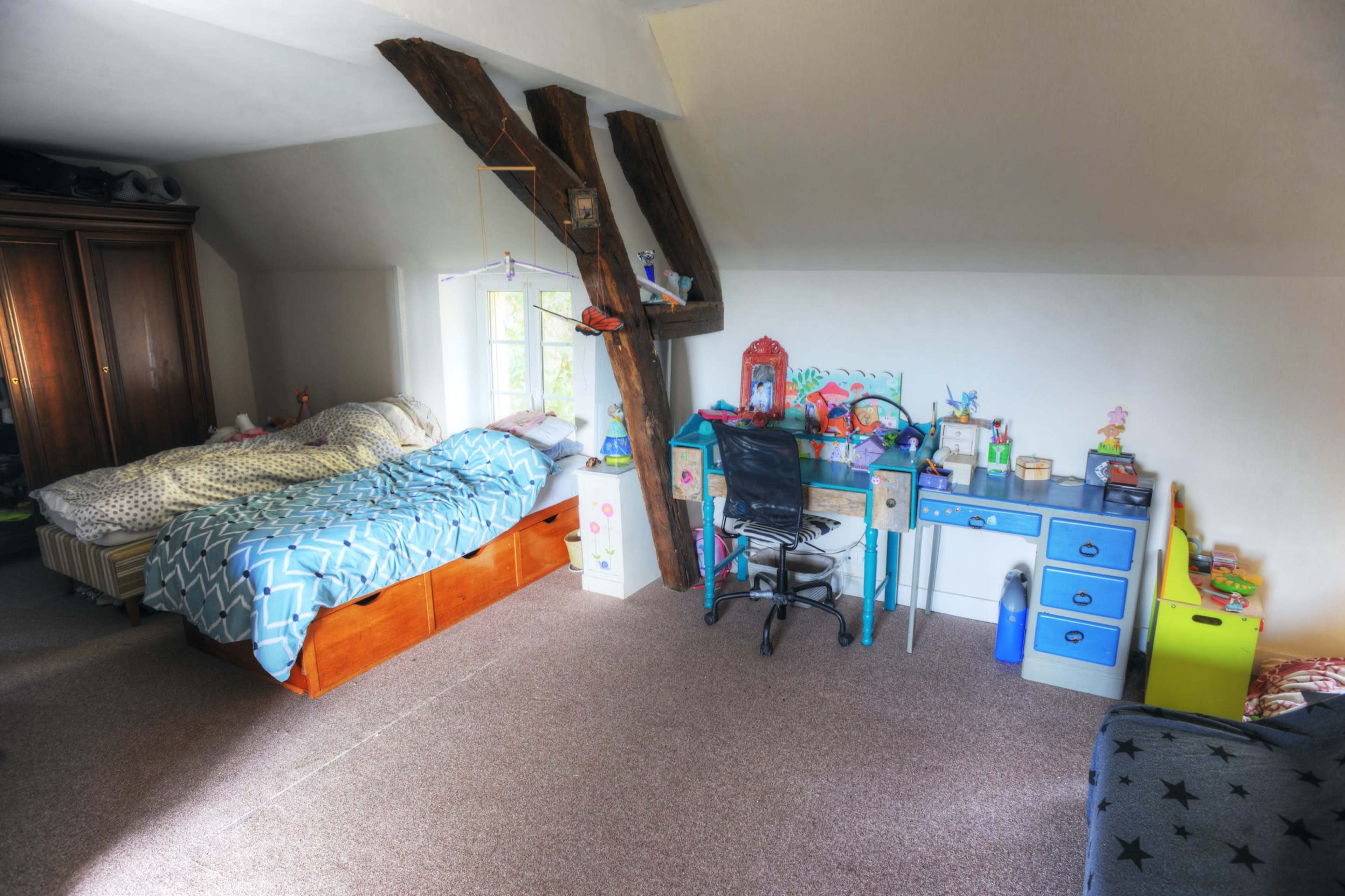 The image depicts a children's bedroom featuring two beds, a desk with a chair, and colorful storage units against the walls.