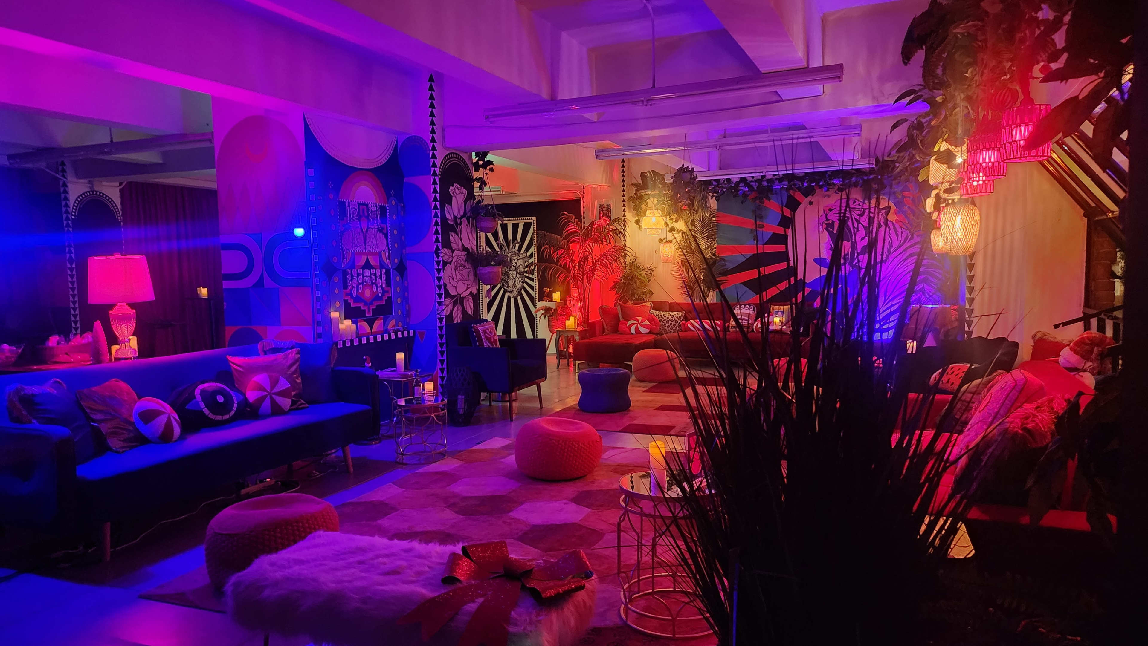 The scene features a vibrant lounge area decorated with colorful patterns, ambient lighting, and plush seating arrangements.