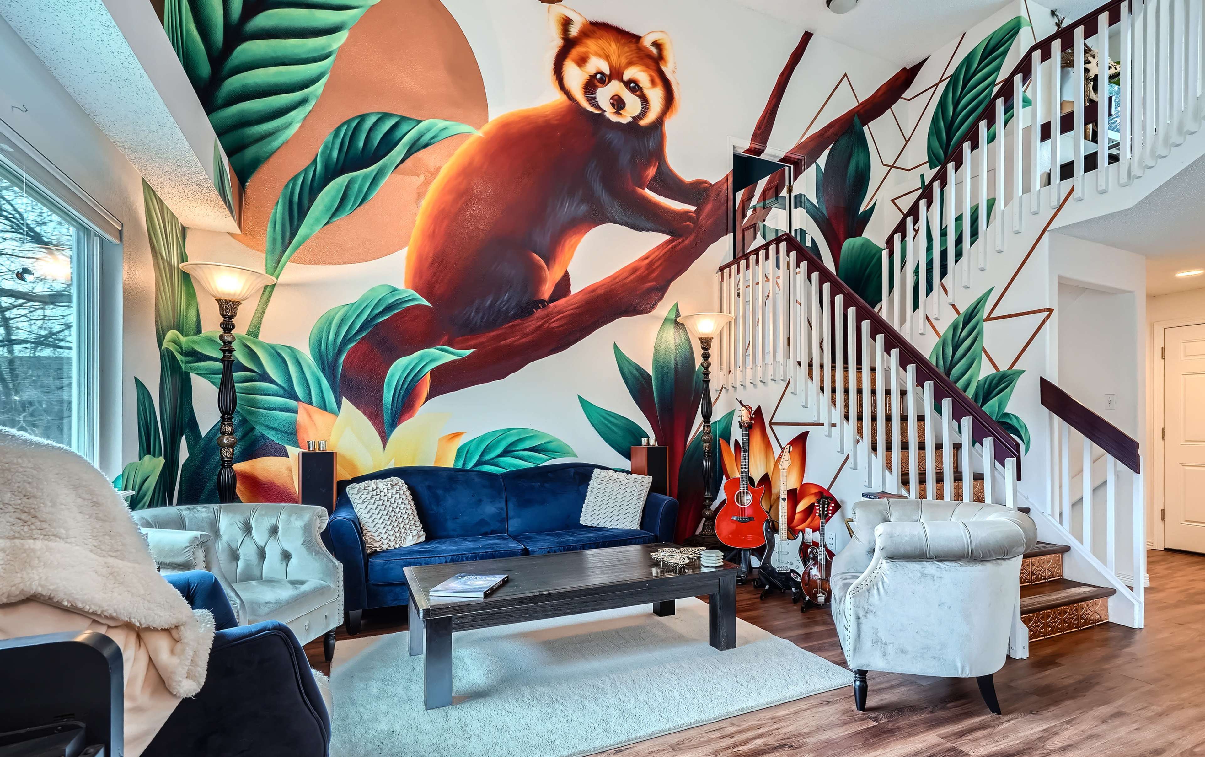 A vibrant mural of a red panda adorns the wall beside a staircase in a room furnished with a blue couch and various decorative elements.
