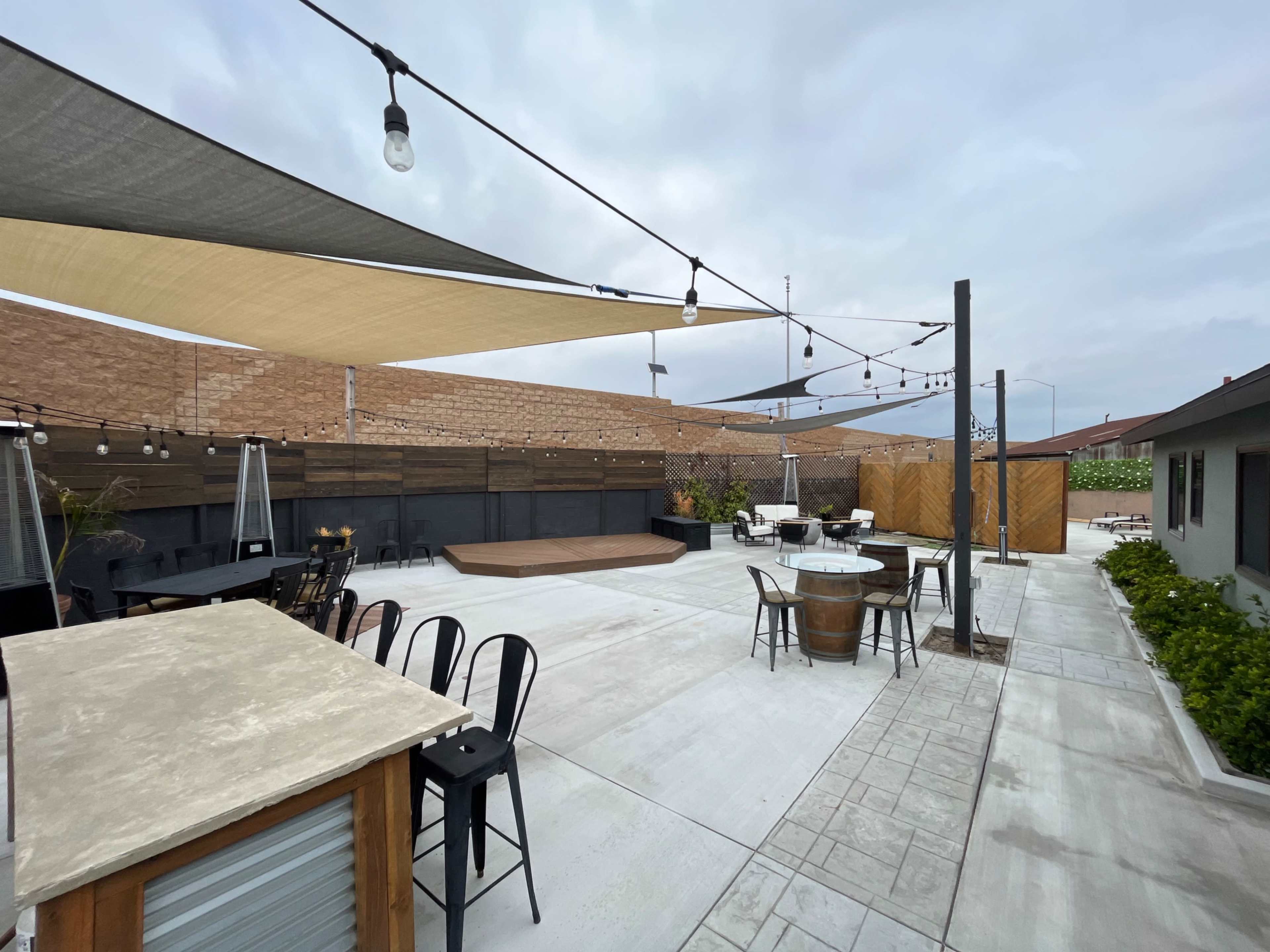 A spacious outdoor patio area featuring seating arrangements, decorative lighting, and shade structures.