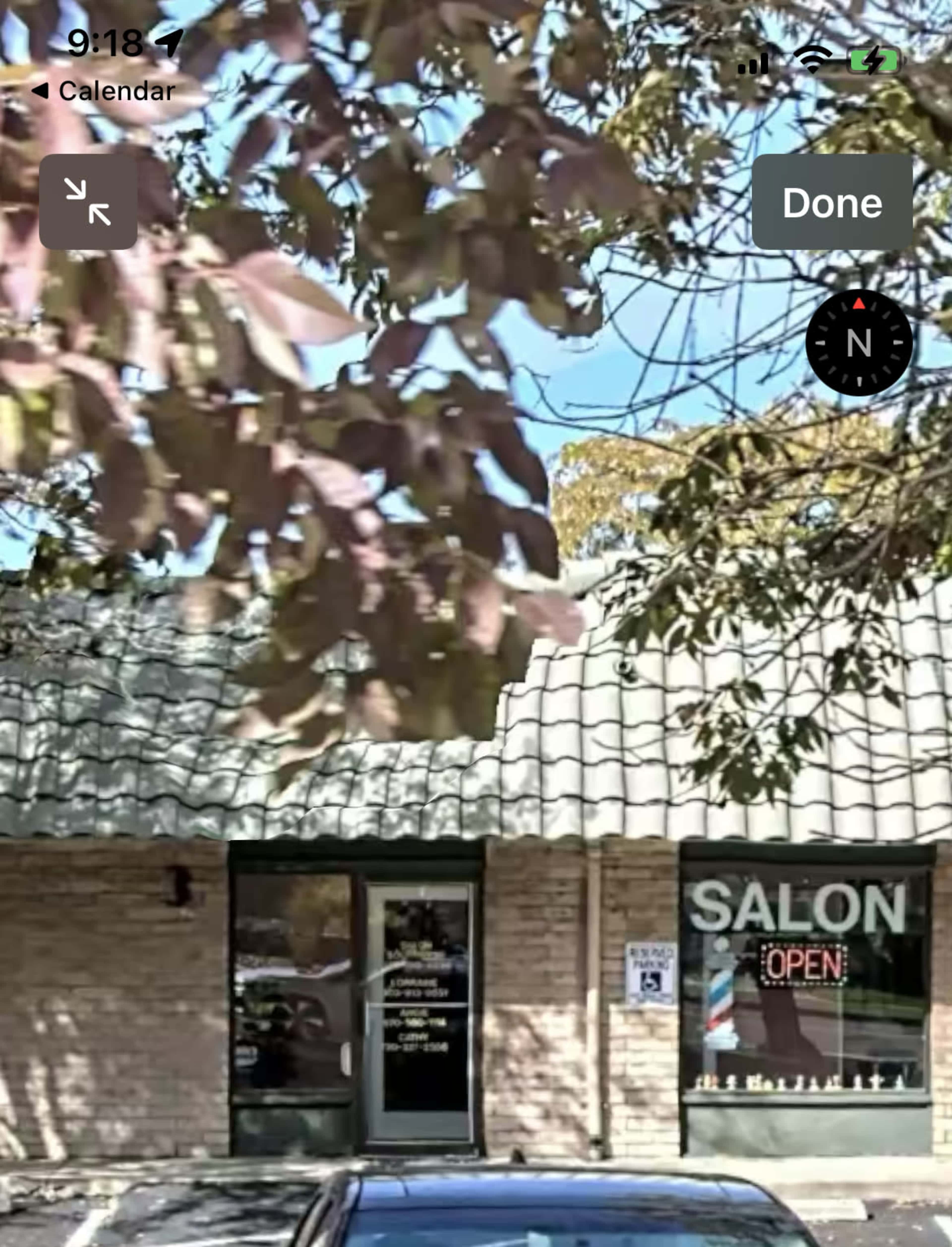 A salon with a sign reading "OPEN" is located in a brick building with a tiled roof.