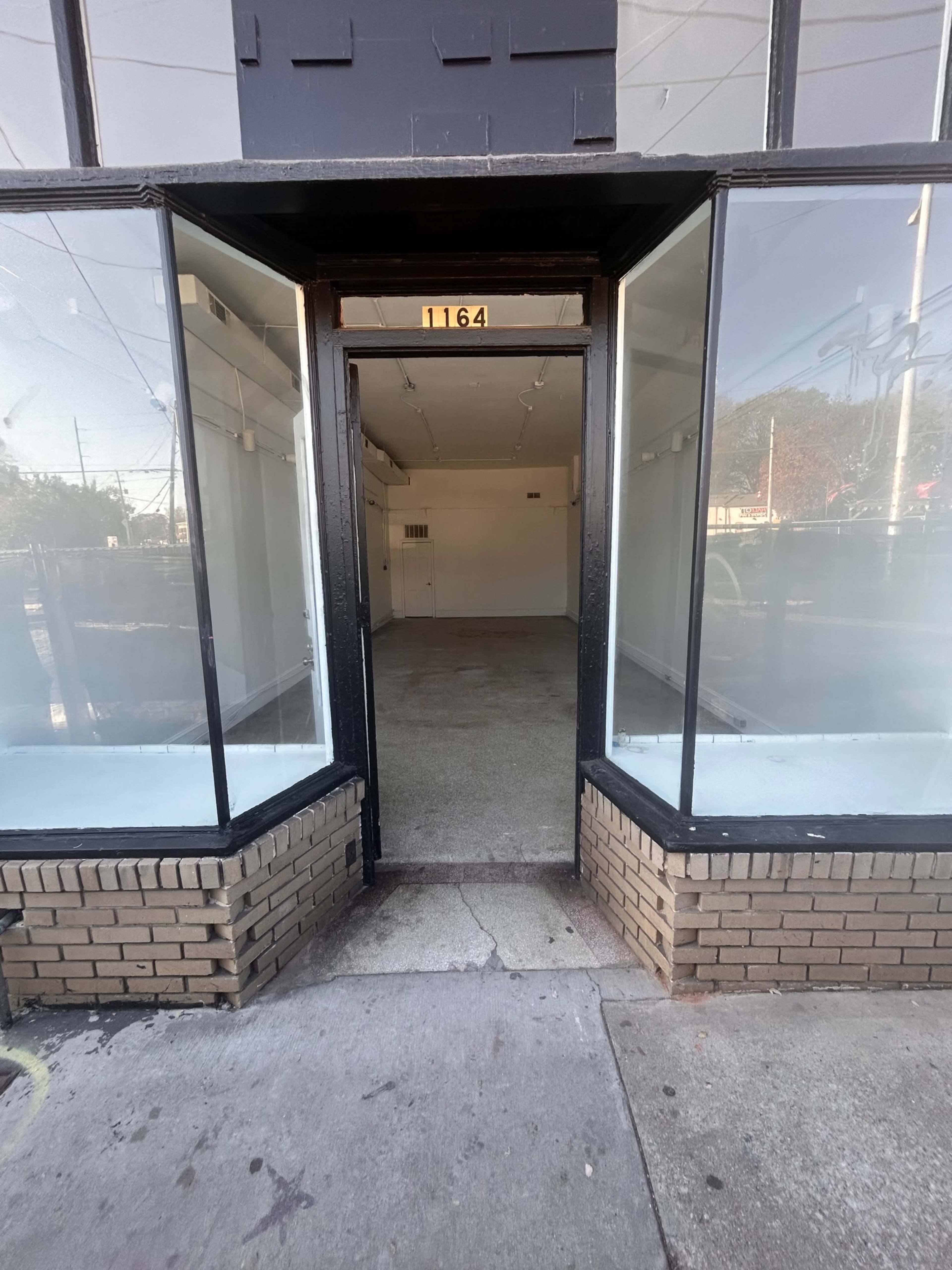 The image shows an empty retail space with large glass windows and a door leading into a vacant interior.