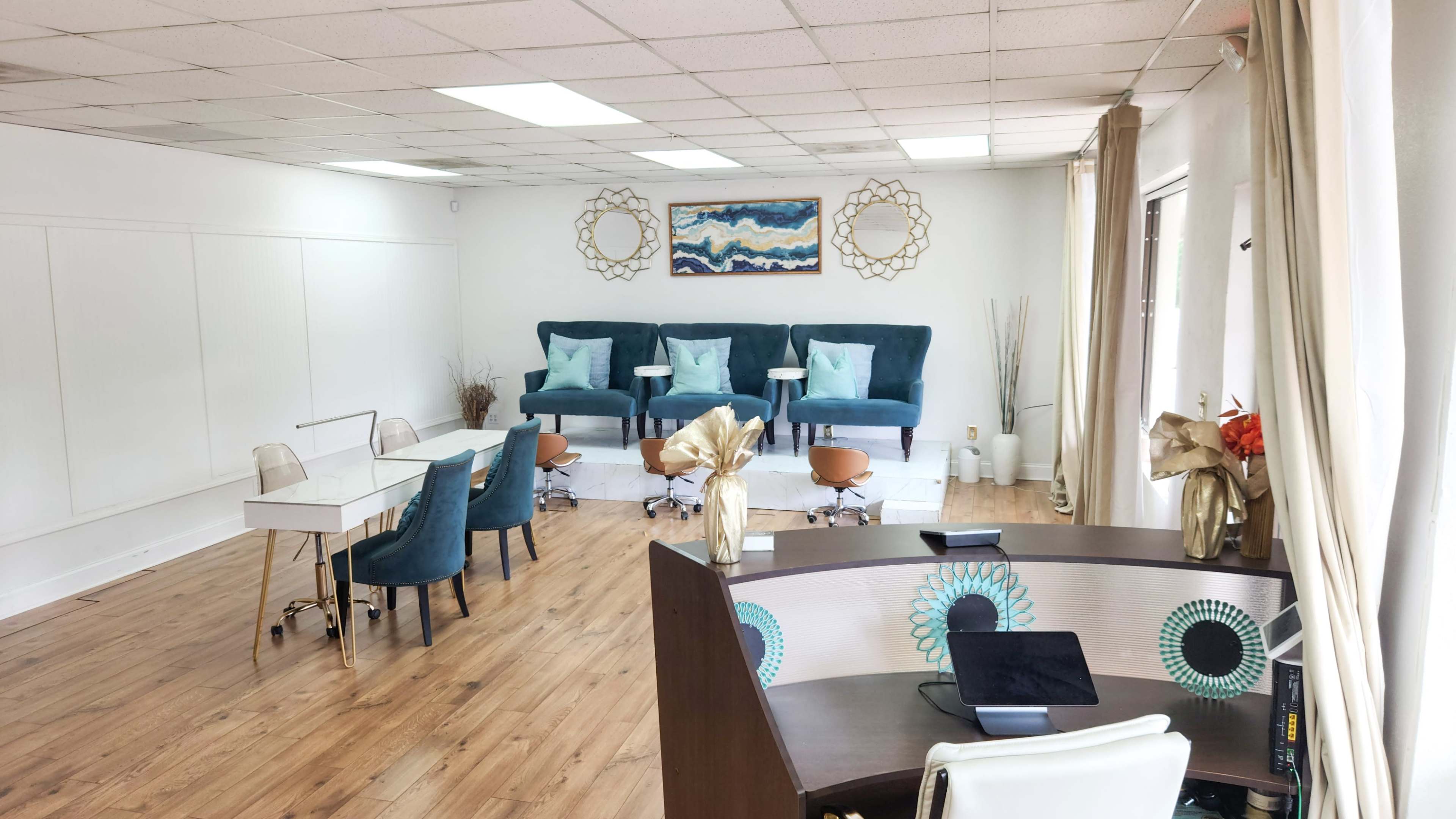 The image shows a well-lit room featuring green upholstered seating, a small office desk, and decorative wall art.