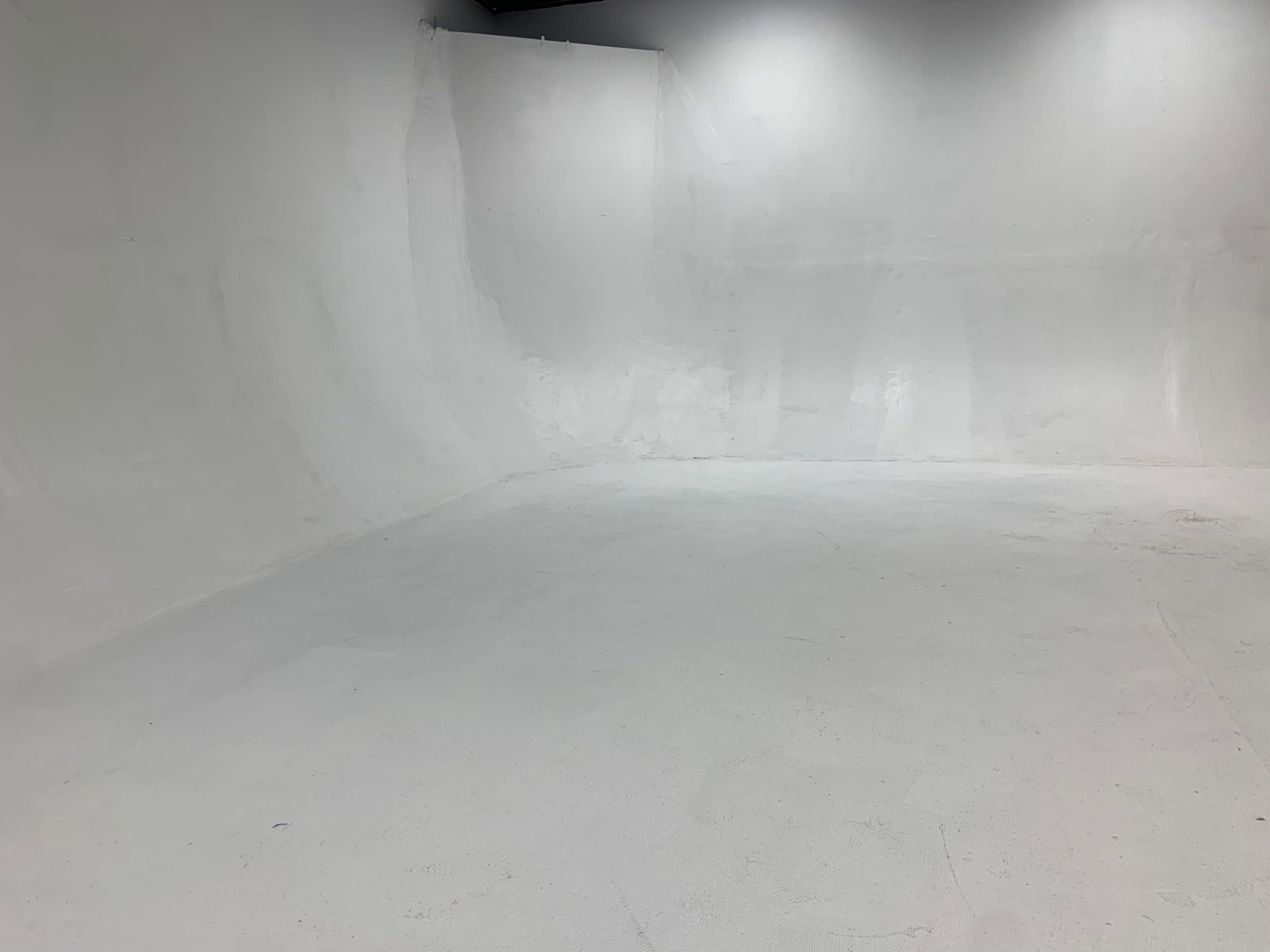 A spacious, empty room with white walls and a smooth white floor.
