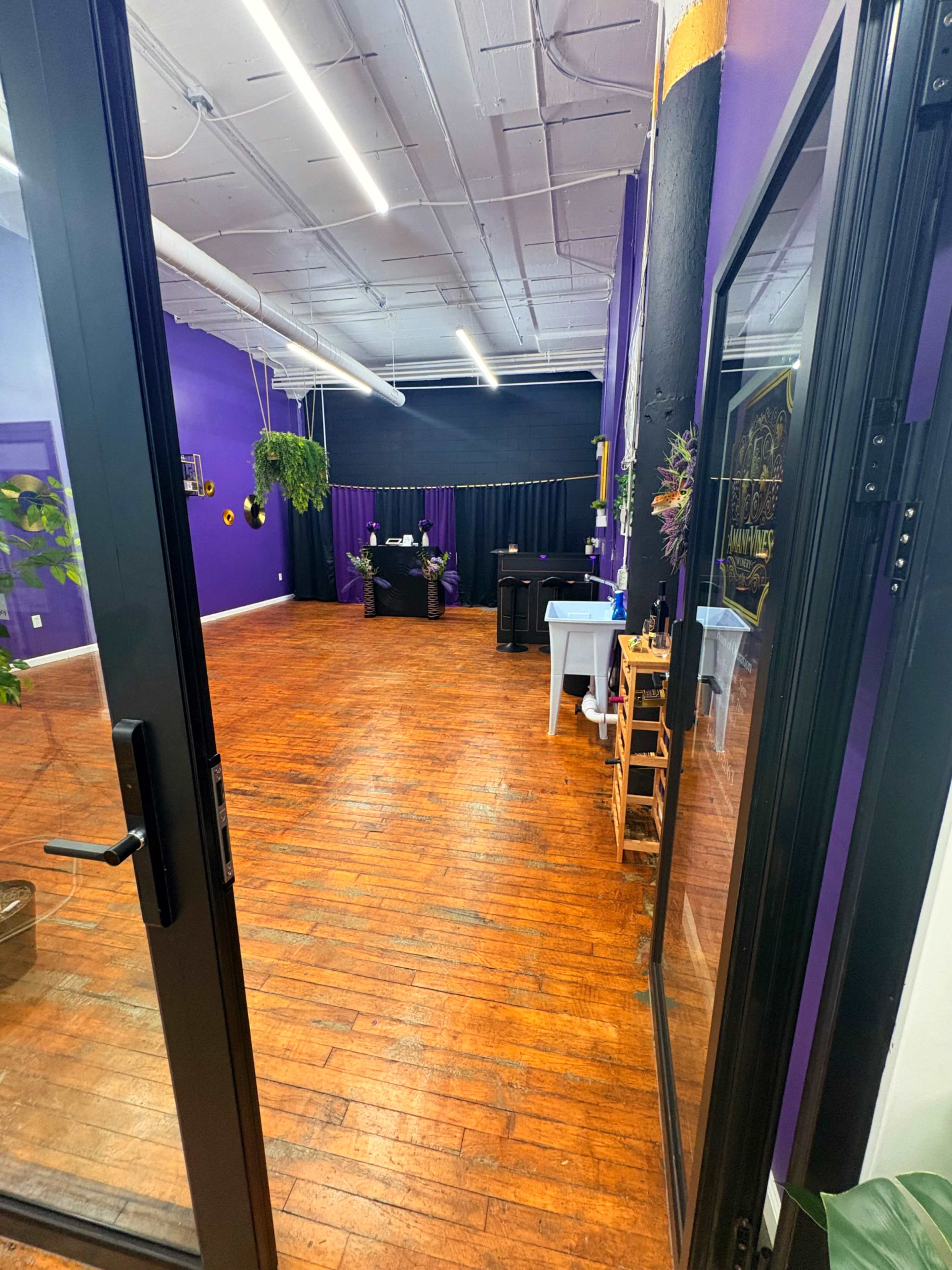 The image shows the interior of a purple-painted room with wooden flooring and a reception area at the back.