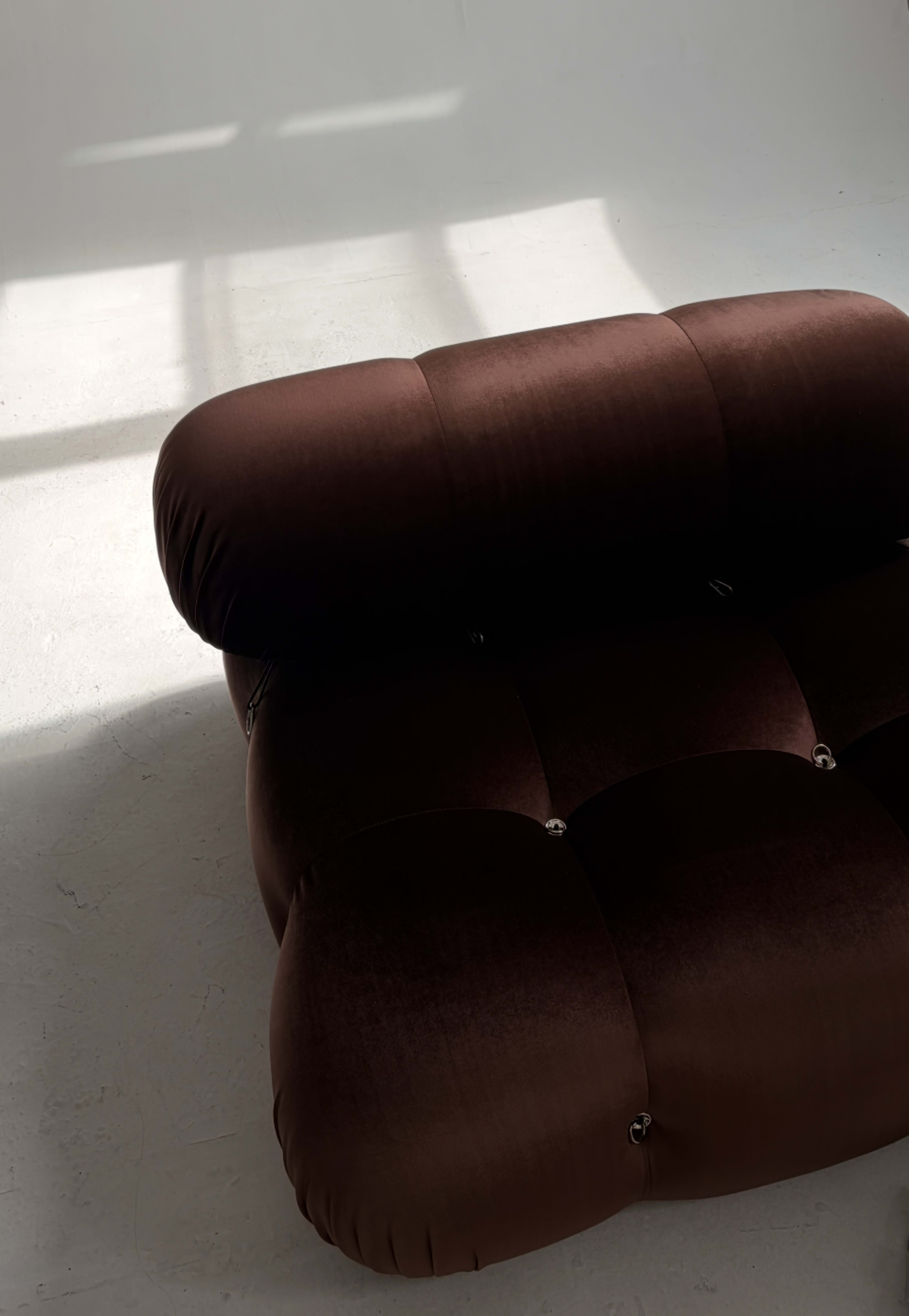 The image shows a close-up view of a brown, tufted sofa with a rounded backrest, placed on a light-colored floor.