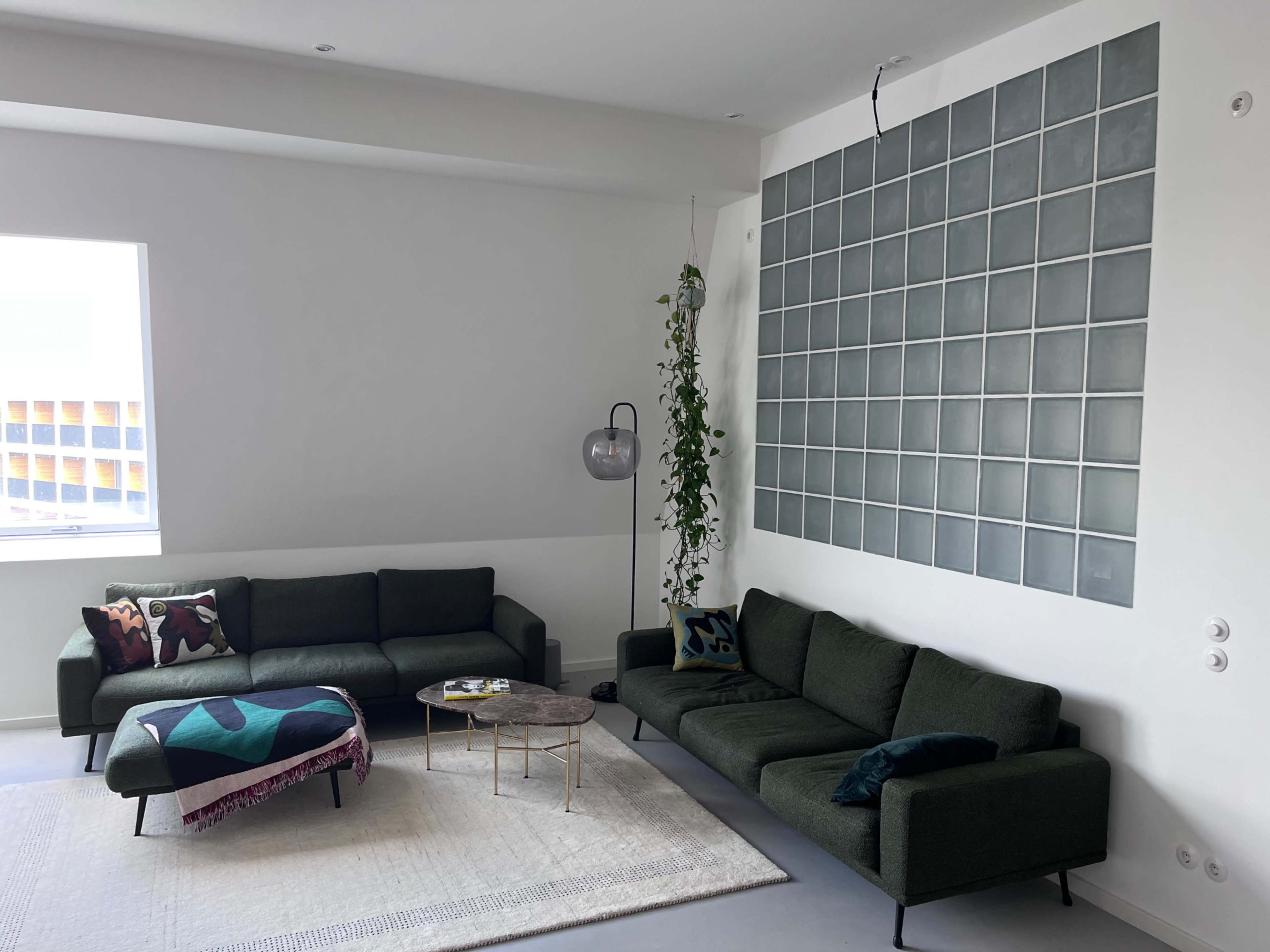 The living room features two green sofas, a glass block wall, and a coffee table on a large area rug.