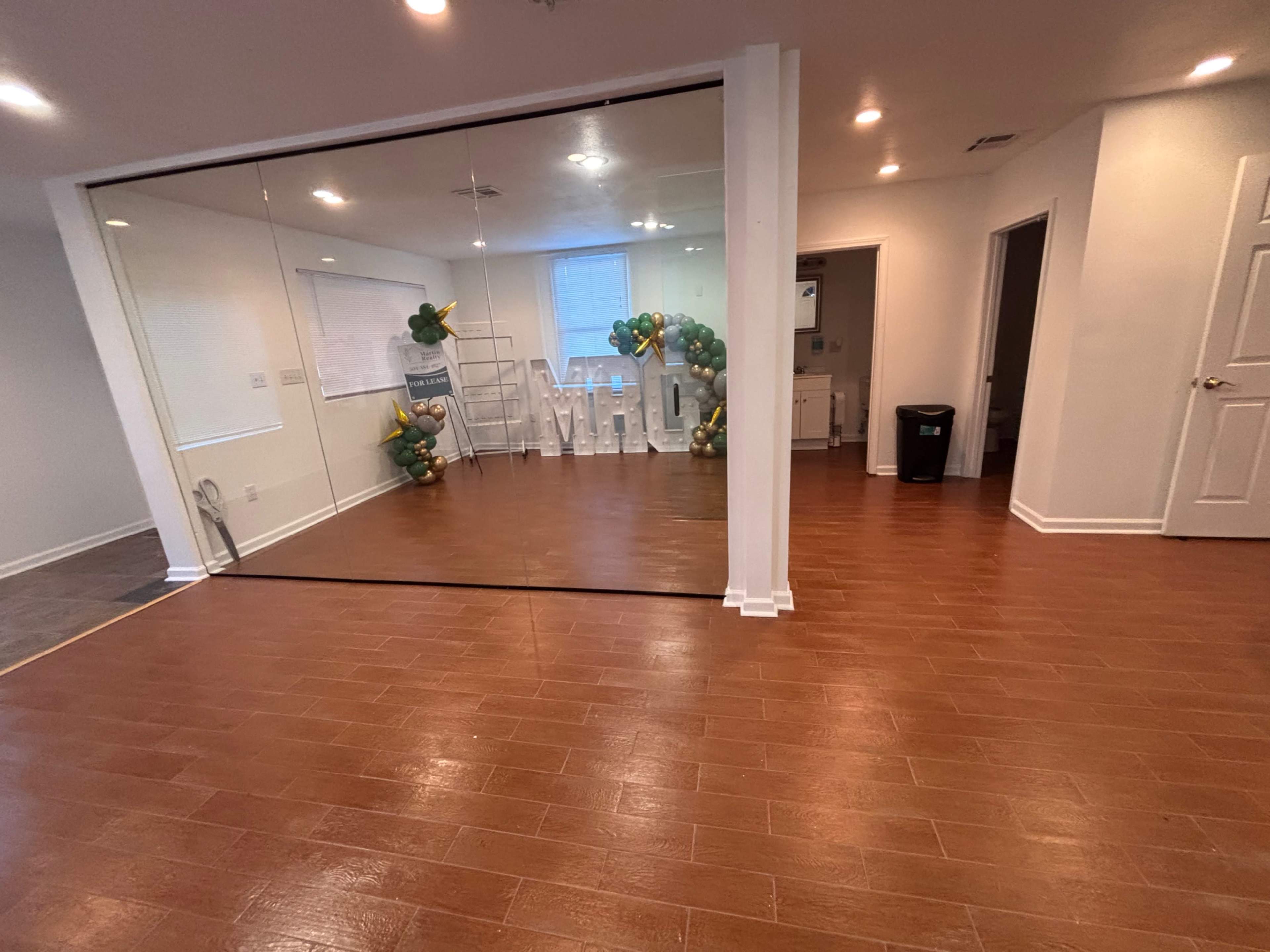 The image shows a spacious interior with a mirrored wall, a decorative arrangement of balloons on one side, and various furnishings visible in the background.