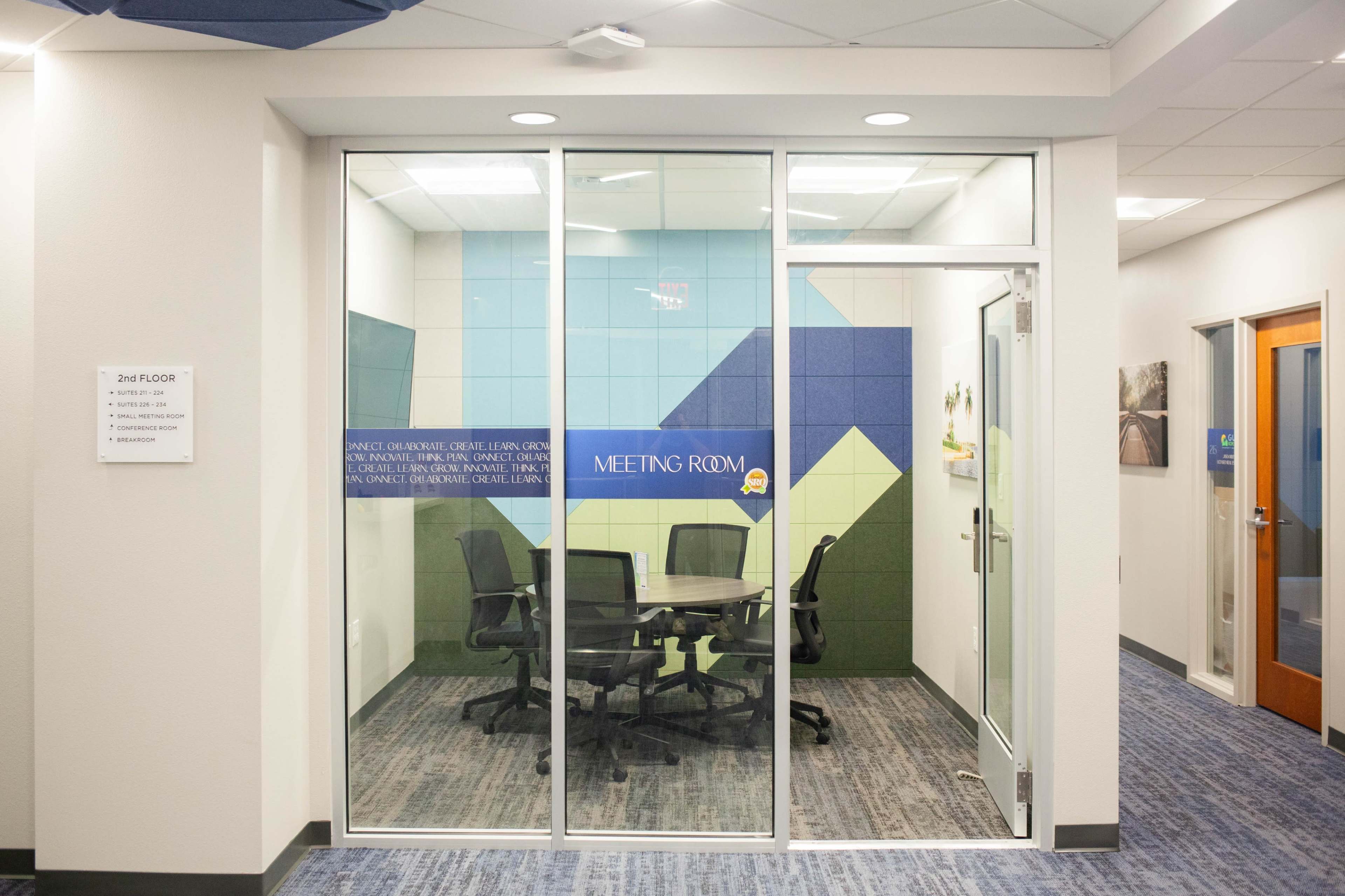 A glass-walled conference room with a dark table and chairs is located on the second floor.