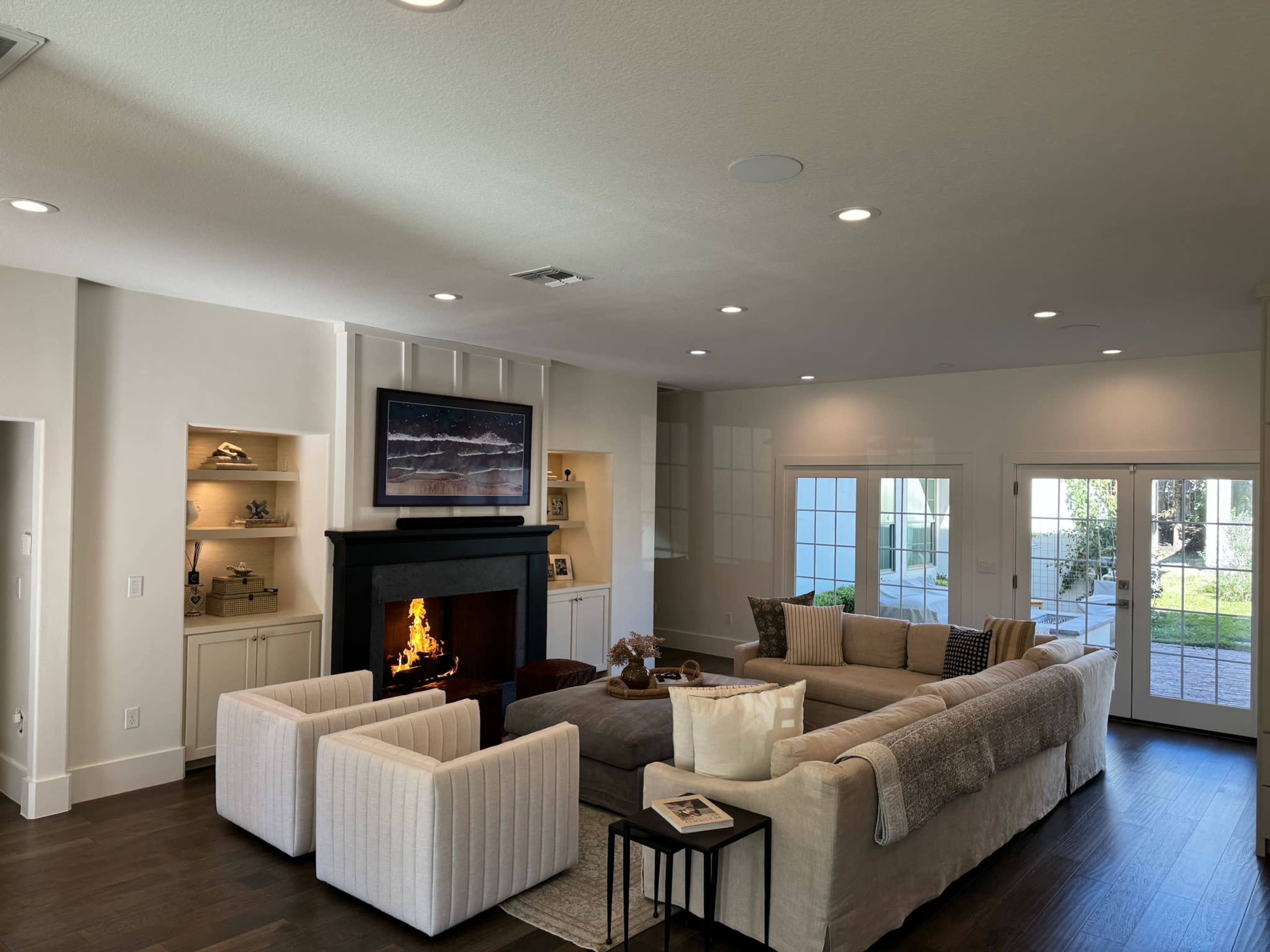 A modern living room with a sectional sofa, a fireplace, and large windows that lead to an outdoor patio.