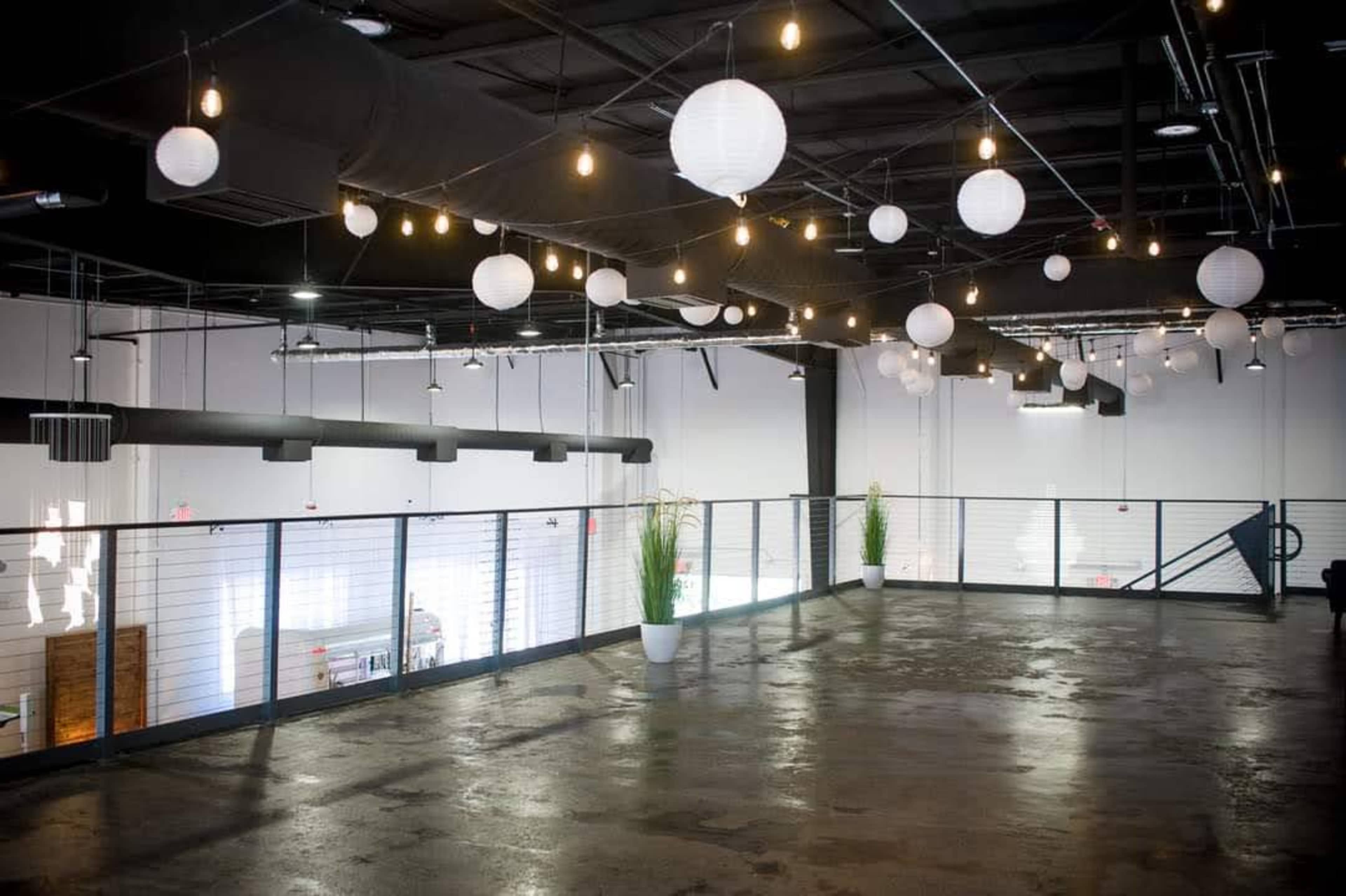 The image shows an expansive open space with a polished concrete floor and paper lanterns suspended from the ceiling.