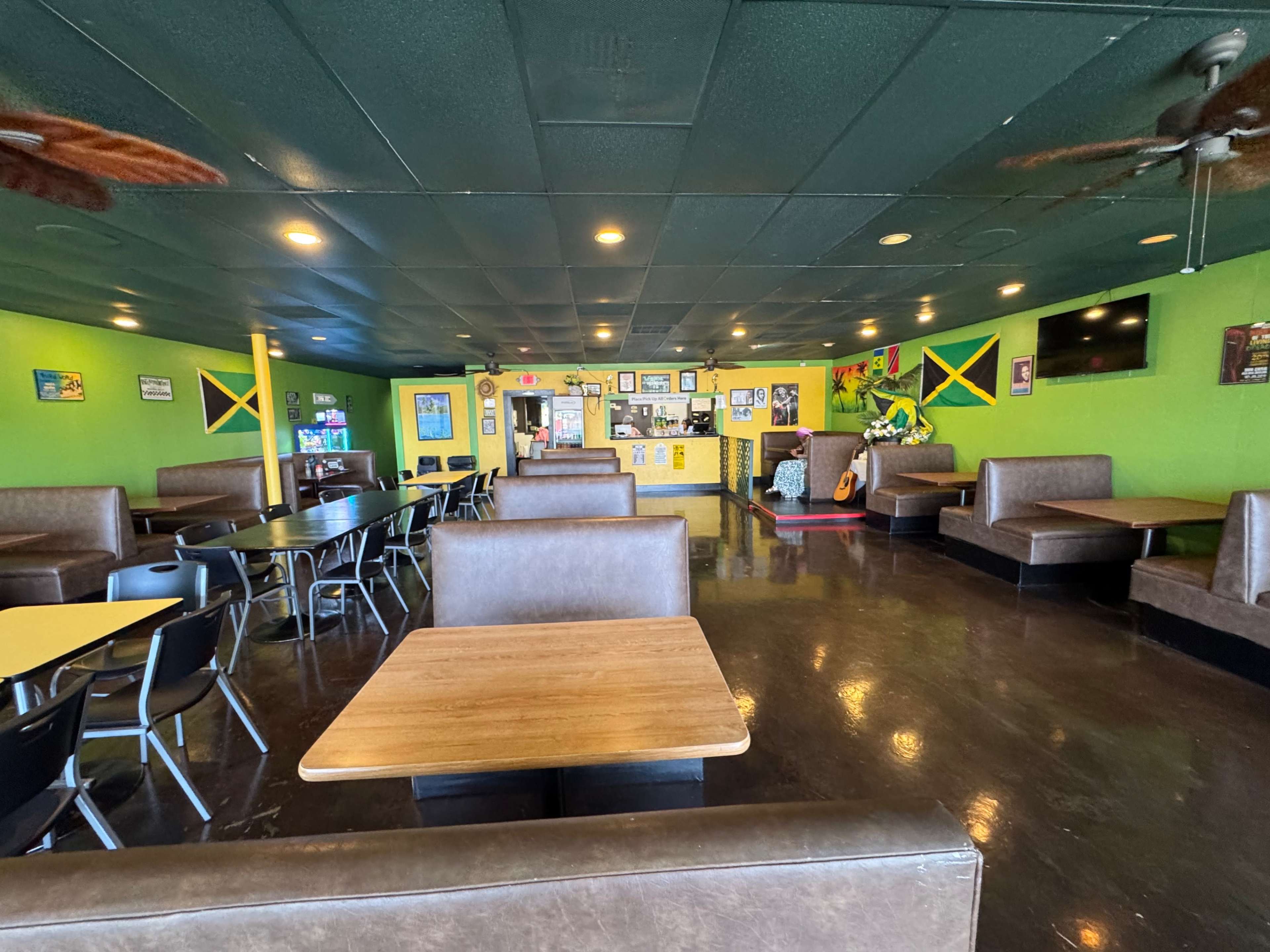 The interior of a brightly colored restaurant features wooden tables and booths along with a counter at the back adorned with various decorations.
