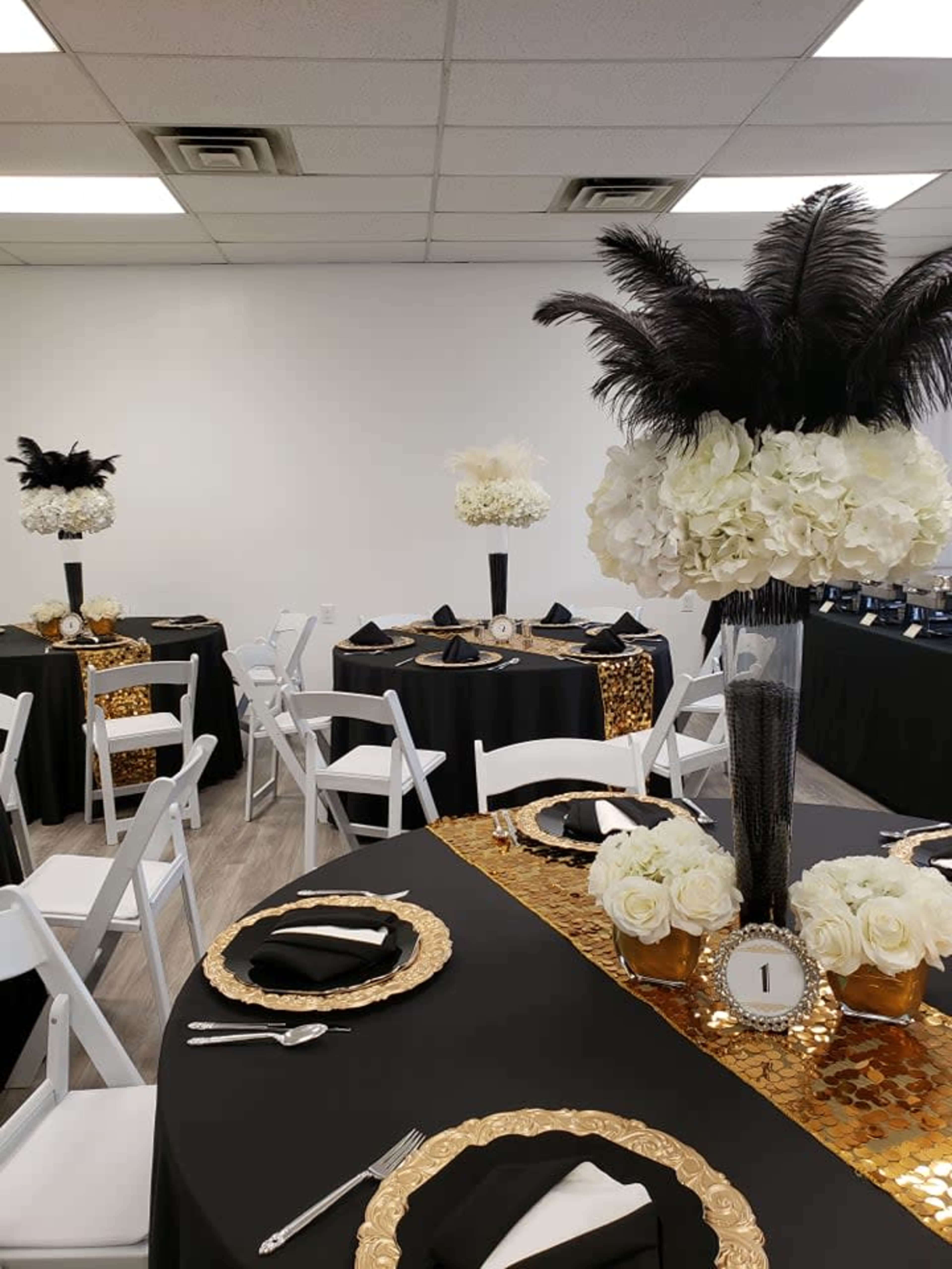 A banquet setup with black and gold tables adorned with floral centerpieces and elegant place settings.