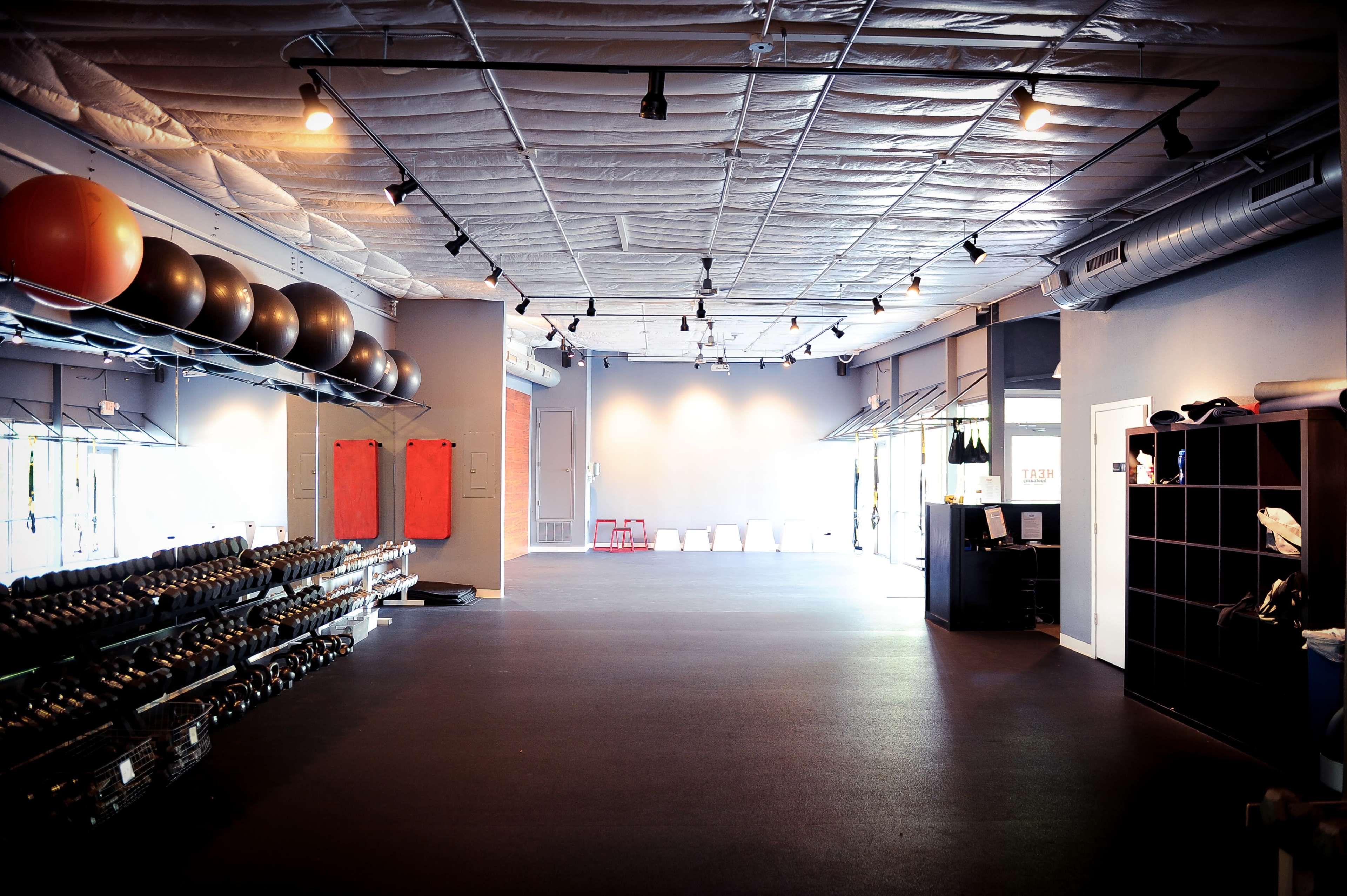 A spacious gym interior with rows of exercise balls and dumbbells neatly arranged against the walls.