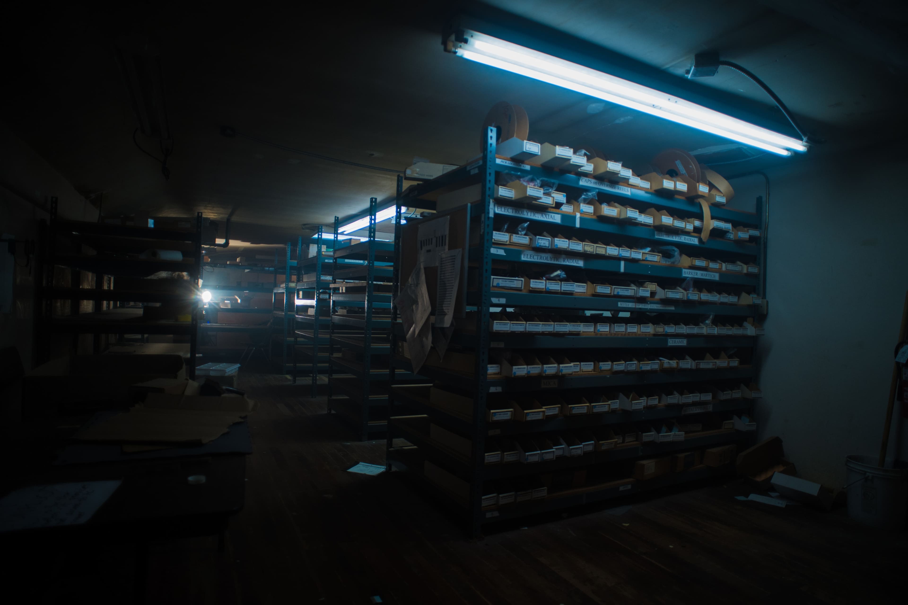 A dimly lit archive room contains metal shelving filled with neatly organized files and documents.