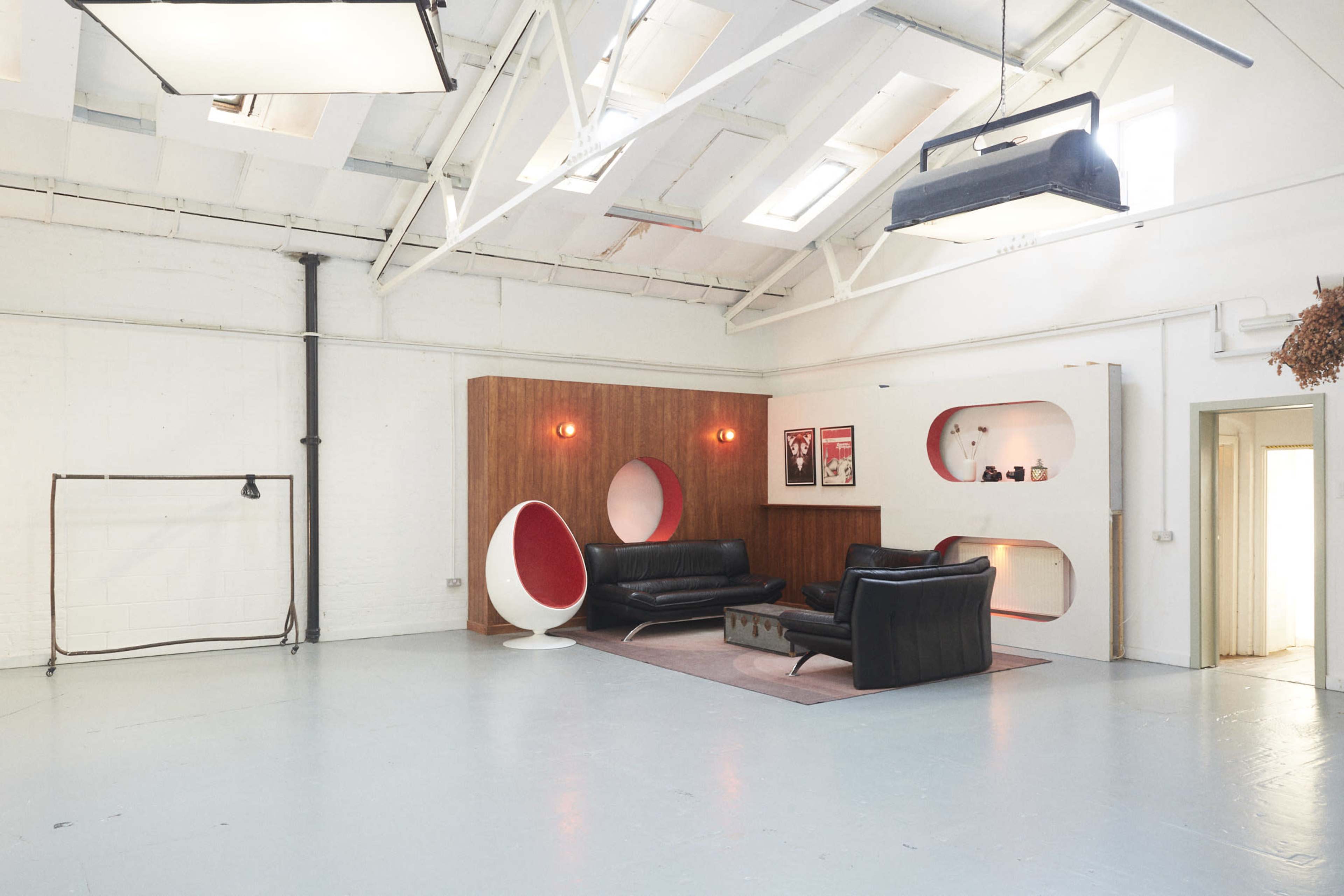 A spacious interior with a modern design, featuring a black leather sofa, a stylized white egg chair, and decorative wall niches with lighting.