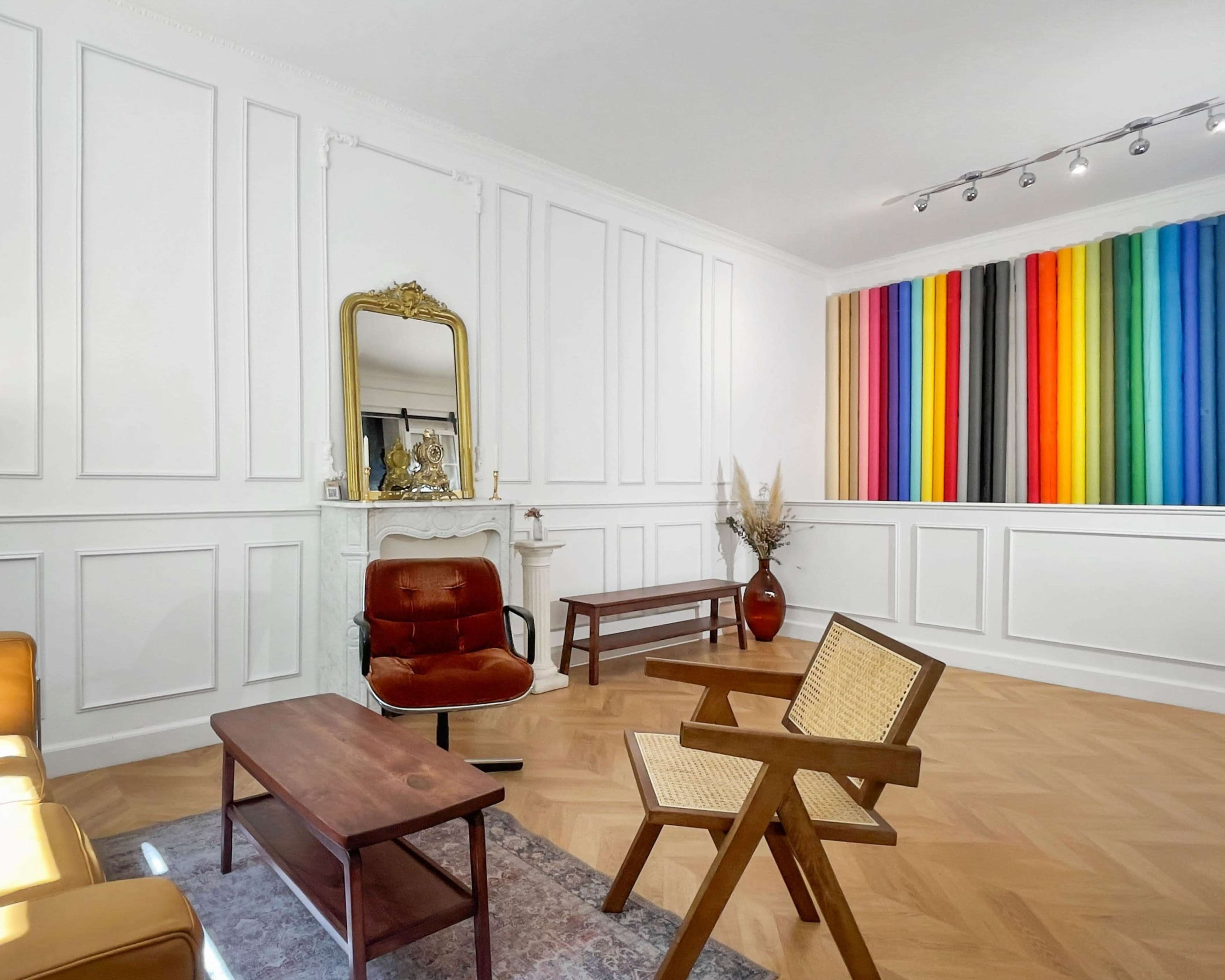 The image shows a modern living room featuring a vintage-style mirror above a fireplace, a colorful wall with vertical stripes, and minimalist furniture arranged on a hardwood floor.